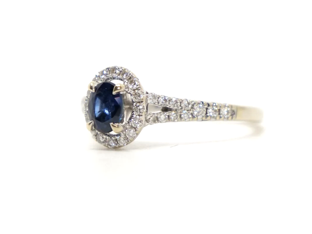 Very pretty 18ct gold sapphire and diamond ring, set with an oval cut sapphire and surrounded by diamonds. With split shank diamond shoulders.