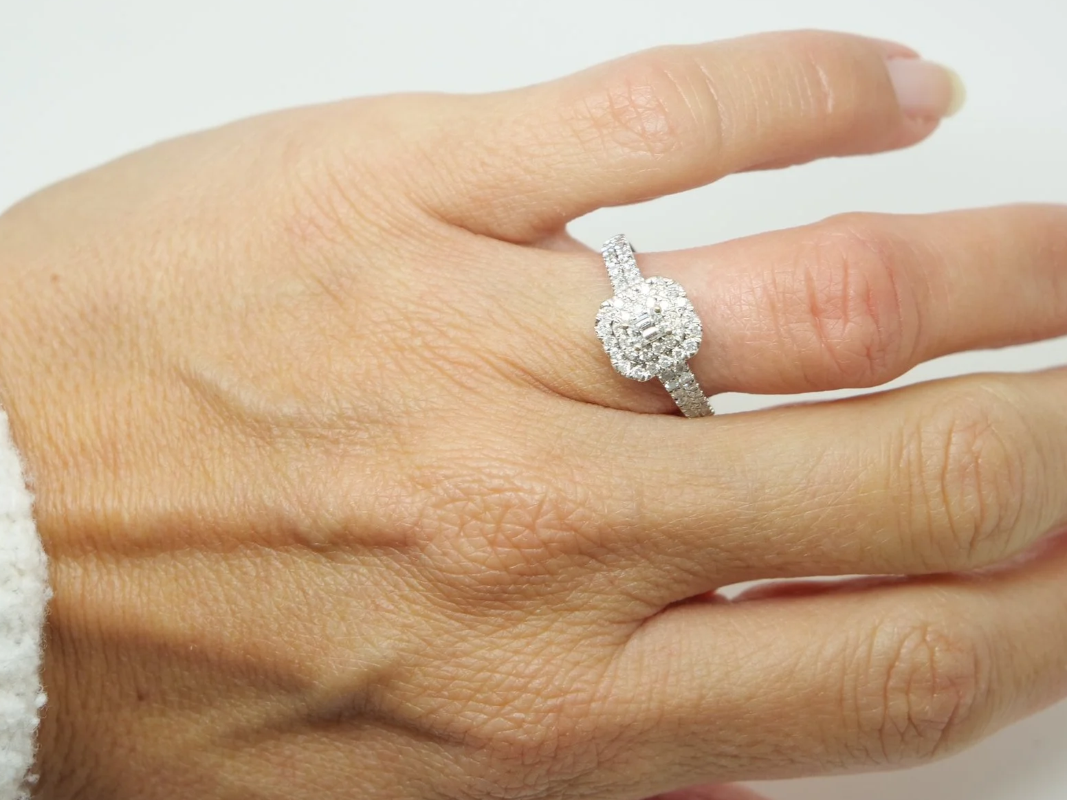 Very sparkly contemporary 18ct gold diamond cluster ring, set with a central emerald cut diamond and surrounded by further brilliant cut diamonds.