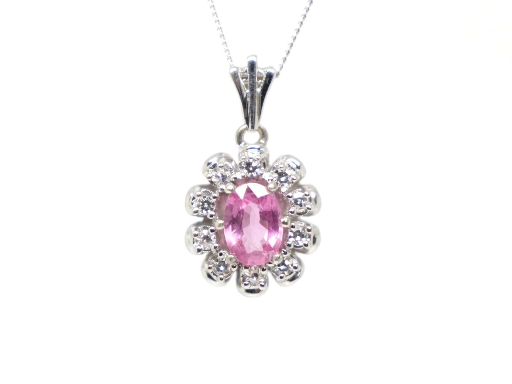 vintage 14ct white gold pink sapphire and diamond cluster pendant, set with a striking oval cut pink sapphire and surrounded by diamonds.