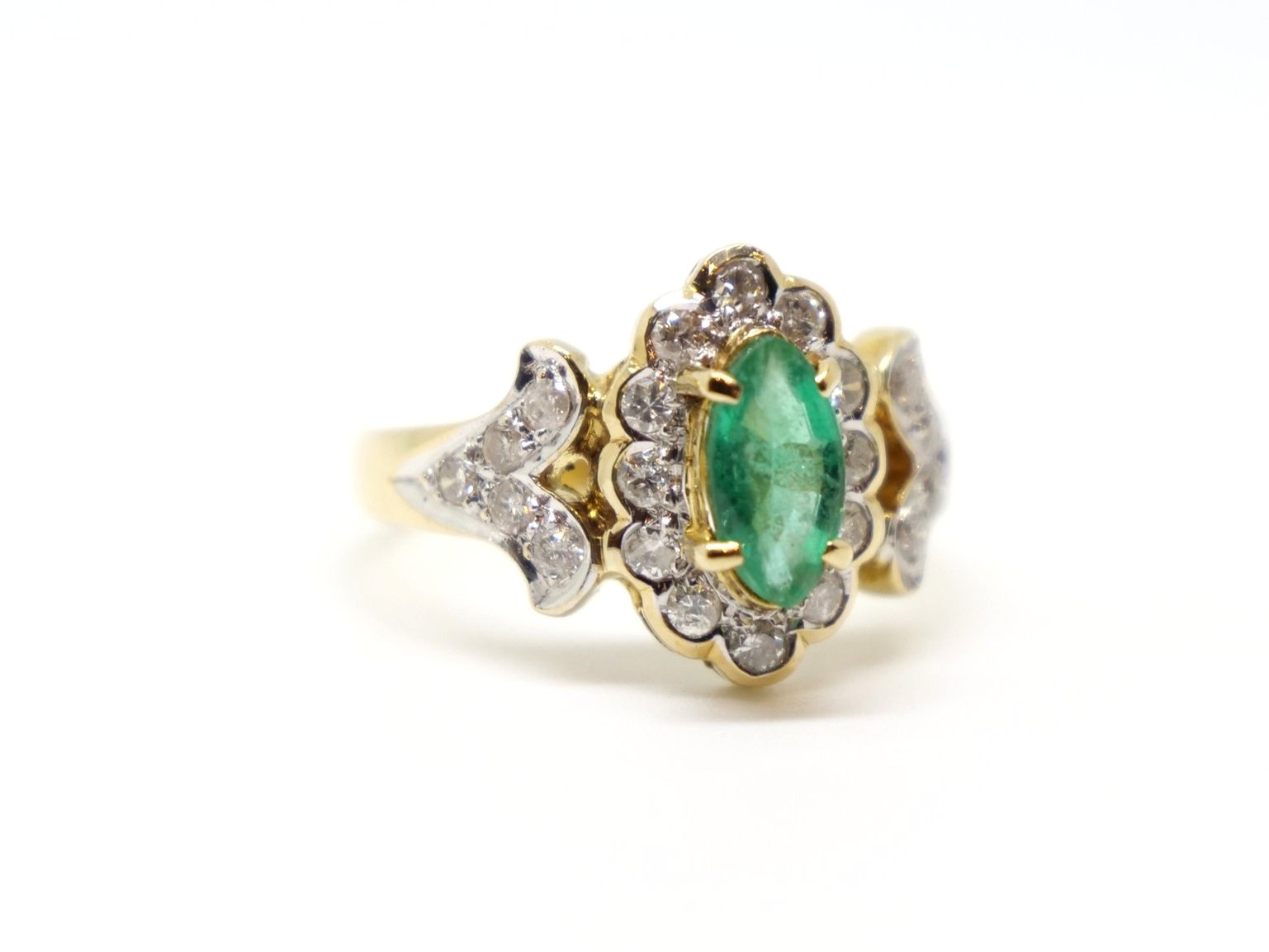 Very unusual 18ct gold emerald and diamond ring, set with a marquise cut central emerald and surrounded by diamonds. Further diamonds to each shoulder.