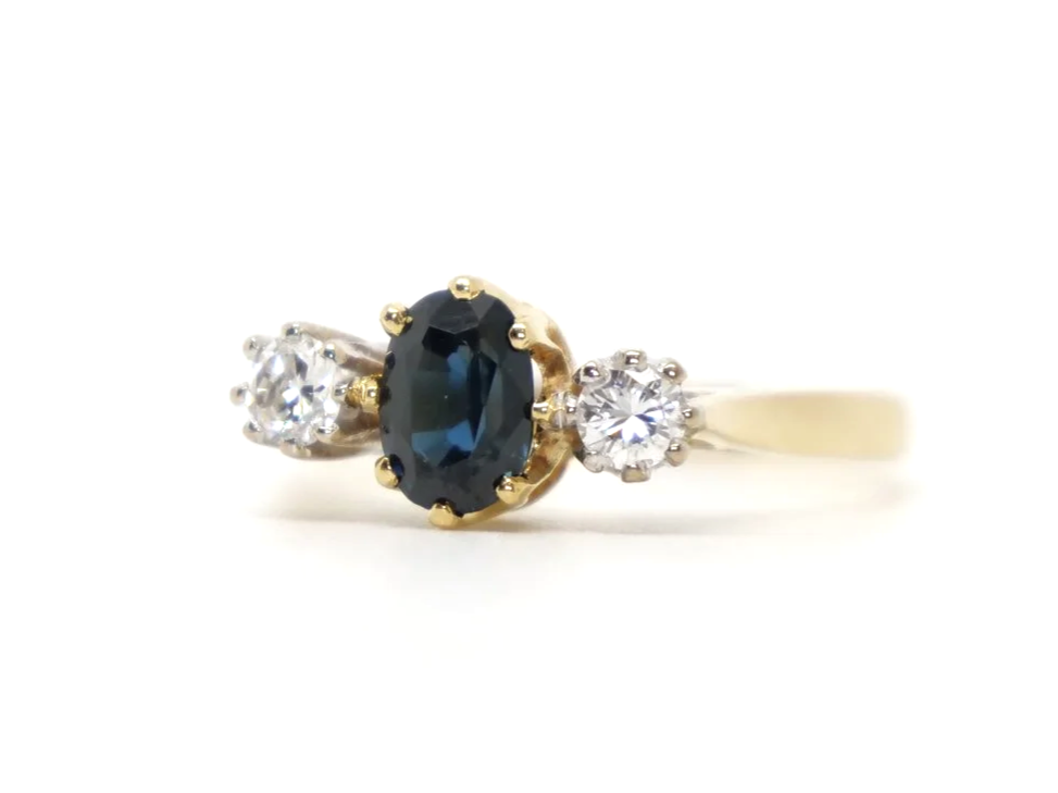 Classic 18ct gold vintage sapphire and diamond trilogy ring, set with an oval cut sapphire with a brilliant cut diamond to each shoulder.