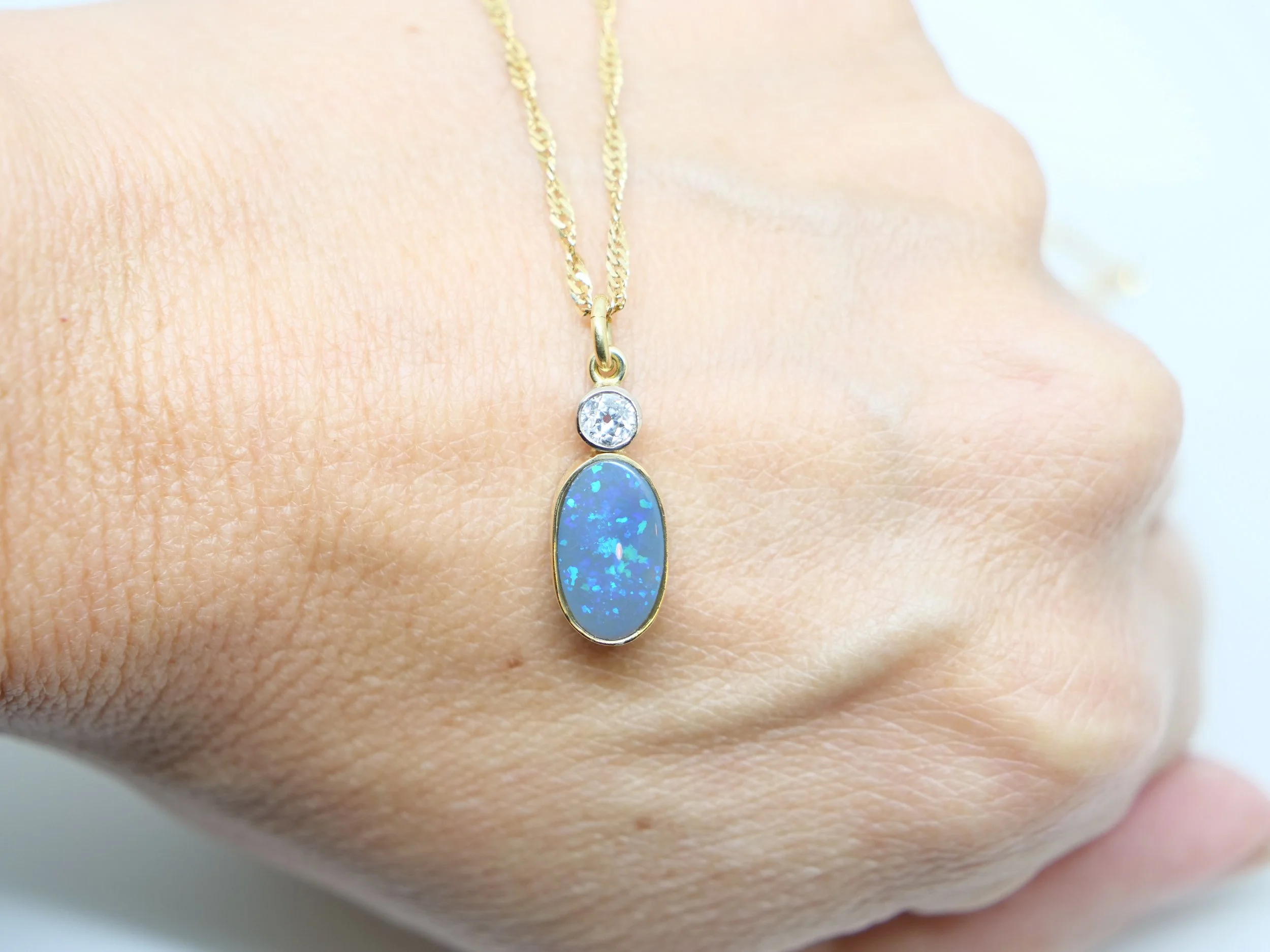 Stunning 18ct gold black opal diamond pendant, set with an oval black opal, with a lovely old cut diamond of approximately 0.25ct. With 18” 18ct gold singapore chain.