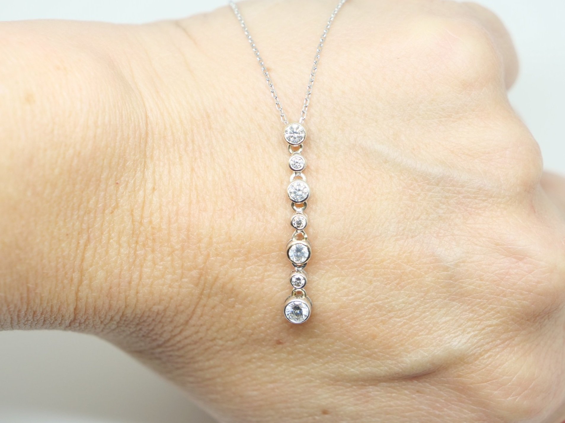 Beautiful 18ct gold drop diamond pendant, with seven different sized bezel set diamonds in this lovely flexible drop design. With 9ct gold chain.