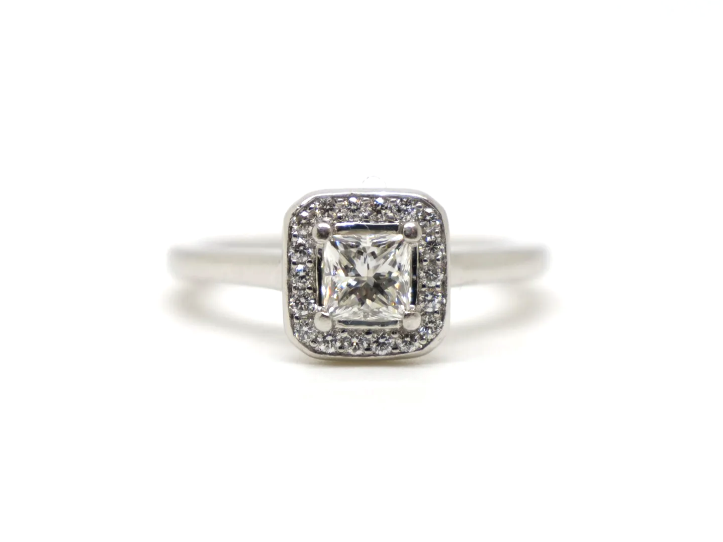 Beautiful platinum diamond ring, set with a central princess cut diamond of excellent quality and surrounded by a halo of diamonds.