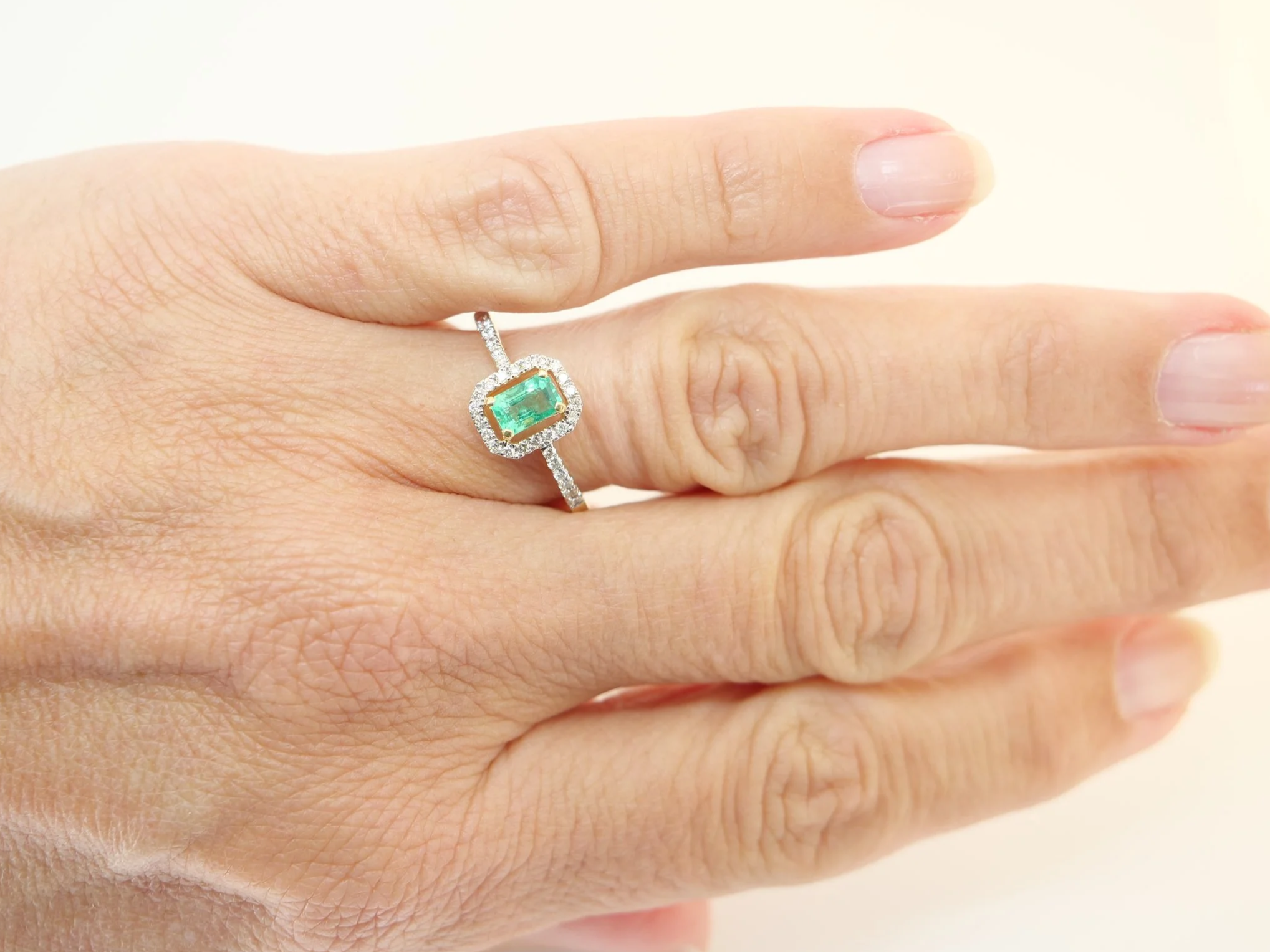 18ct gold emerald and diamond halo ring, emerald cut centre stone