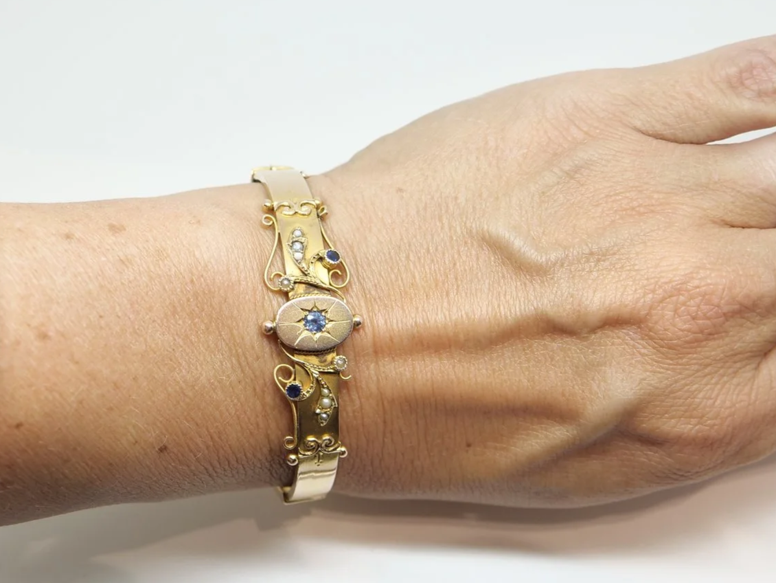 Antique 1907 9ct gold hinged bangle with central star-set sapphire and seed pearl scrollwork