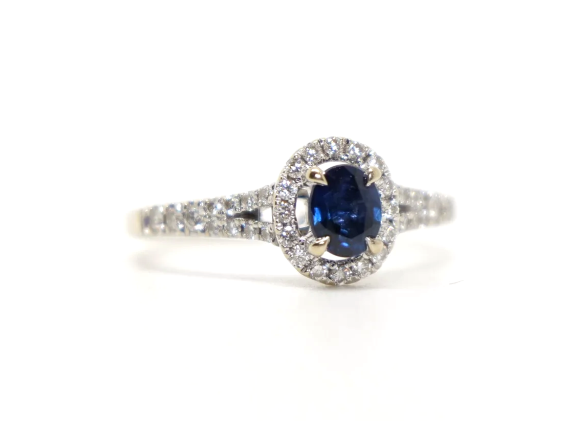 Very pretty 18ct gold sapphire and diamond ring, set with an oval cut sapphire and surrounded by diamonds. With split shank diamond shoulders.