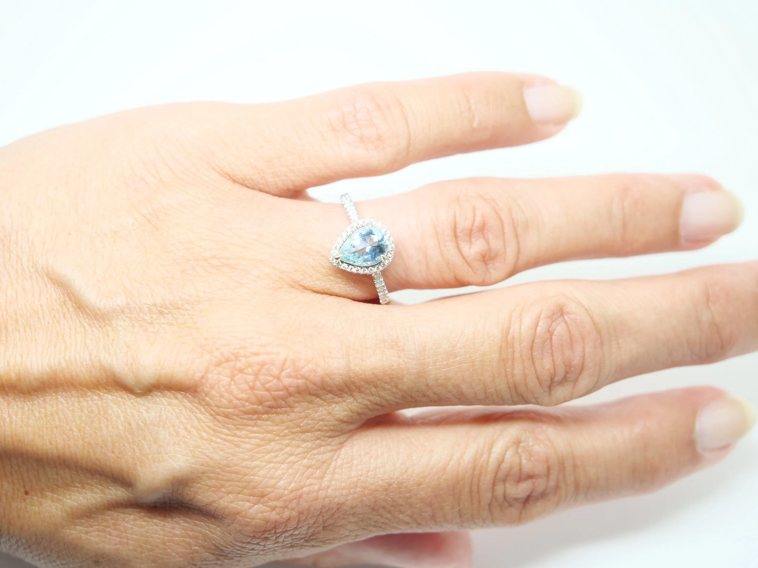 18ct white gold aquamarine and diamond halo ring, set with a pear cut aquamarine at the centre