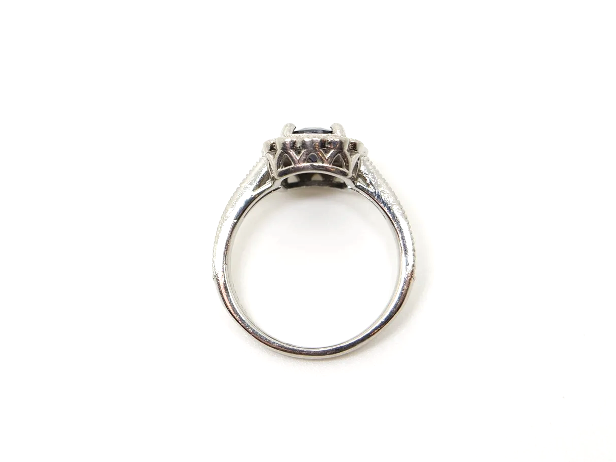 Lovely vintage design platinum ring, set with a large oval cut sapphire and surrounded by diamonds. Further diamonds set into each shoulder.