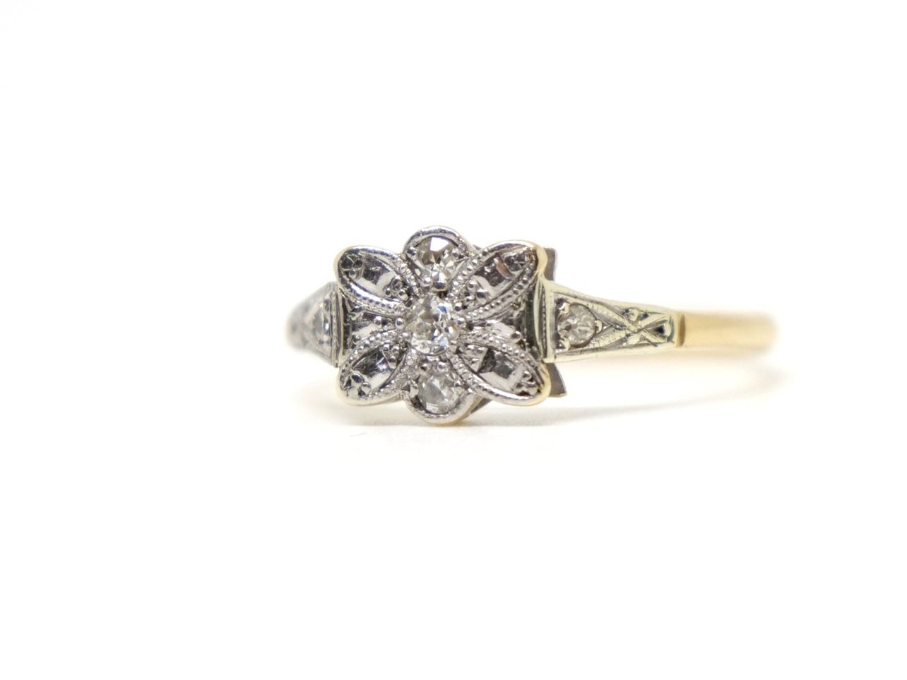 Very pretty 18ct gold Art deco diamond ring, in an unusual floral bow design and set with three small central diamonds. A further diamond set to each shoulder.