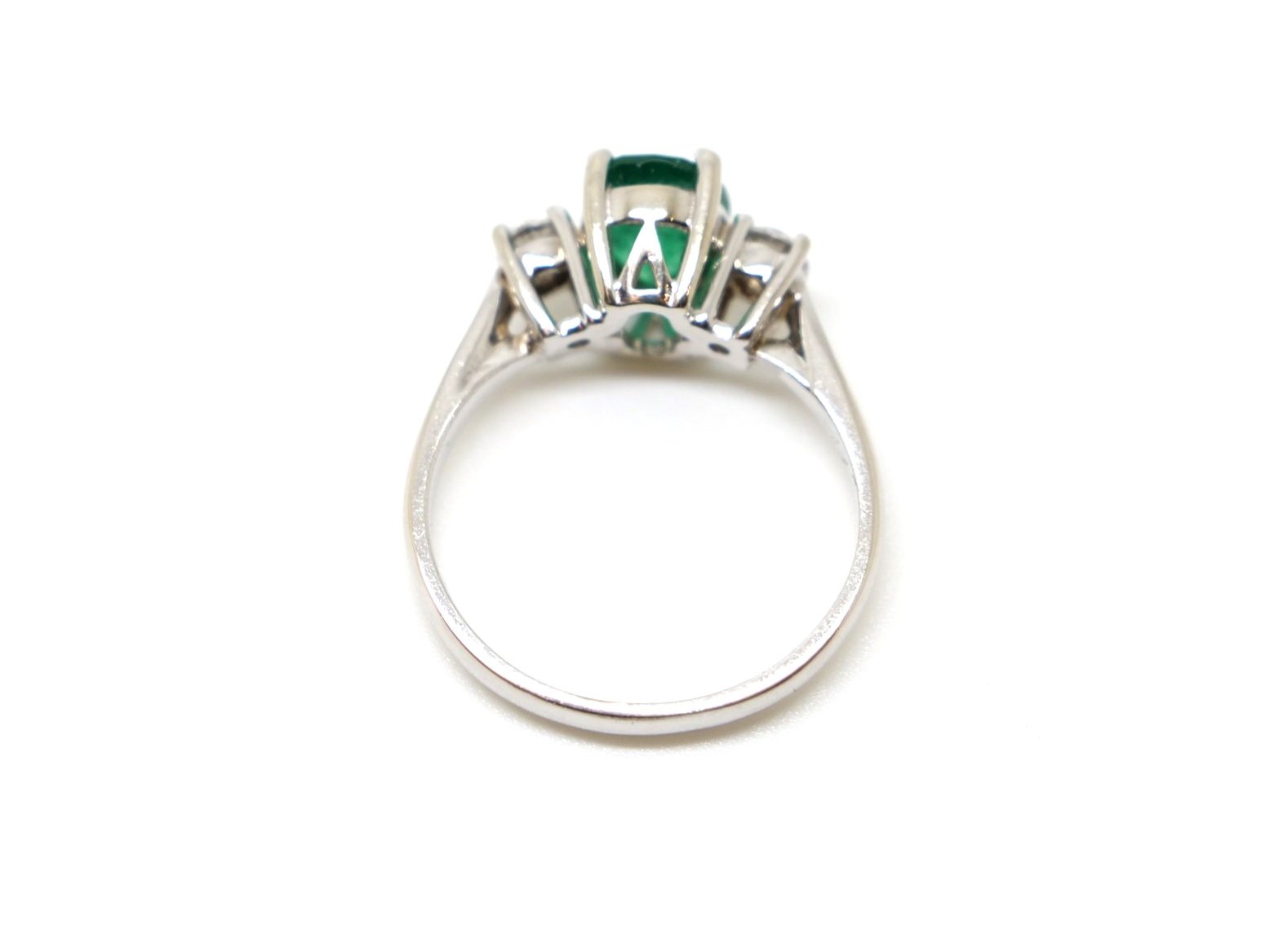 Classic design 18ct white gold emerald and diamond trilogy ring, set with an oval cut emerald of approximately 1.7ct with a brilliant cut diamond to each shoulder.