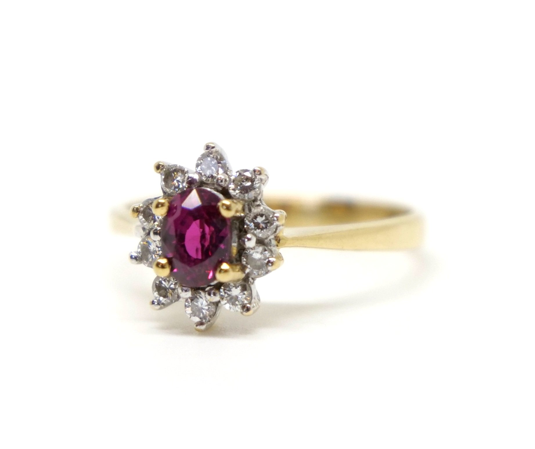 Classic style 18ct gold ruby and diamond oval cluster ring, set woth a central oval cut ruby and surrounded by small diamonds.