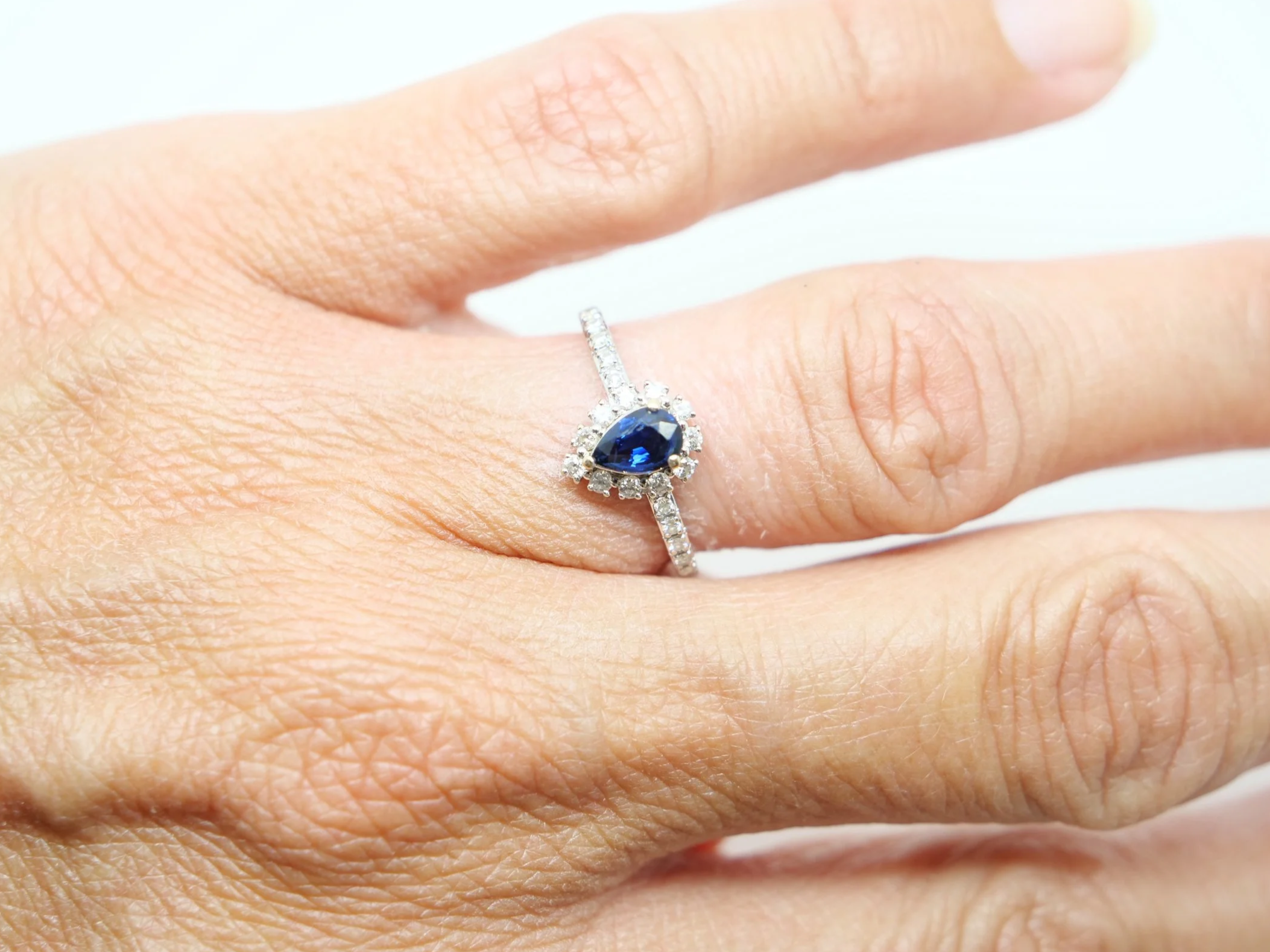 Lovely contemporary 18ct gold pear cut sapphire and diamond ring, with further diamonds set into each shoulder.