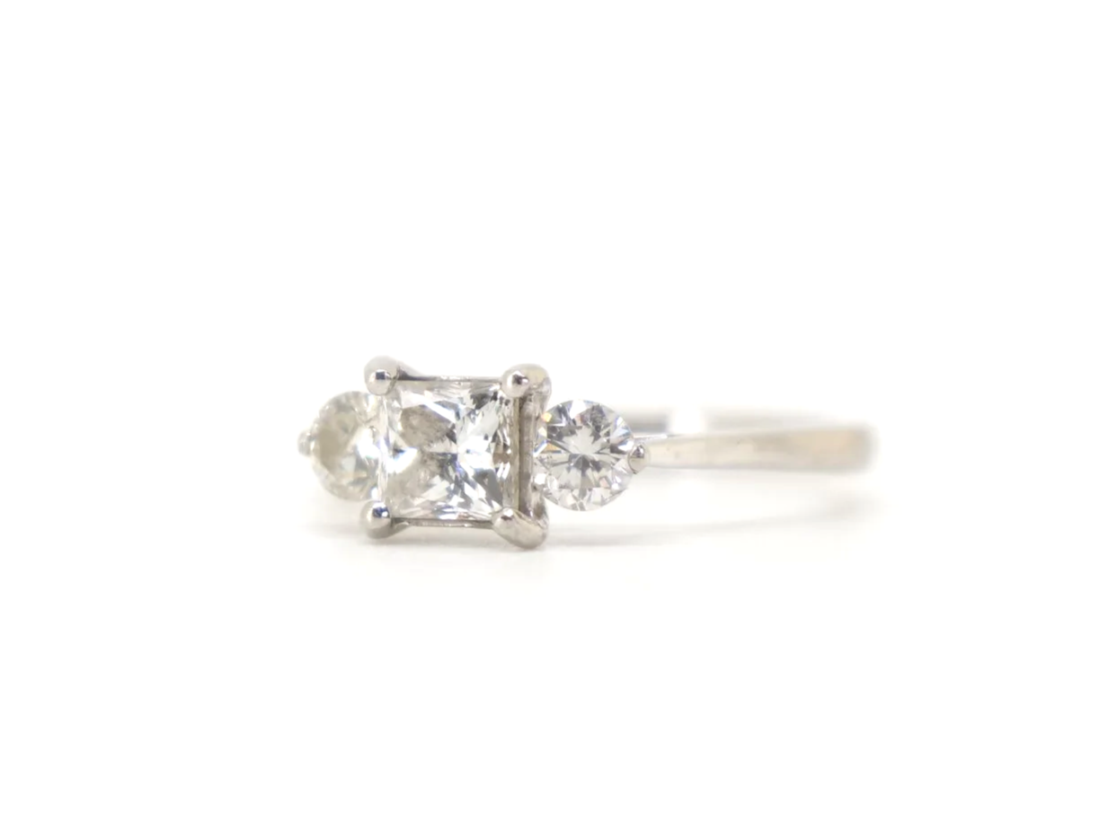Super platinum diamond ring, set with a super princess cut centre diamond, with a brilliant cut diamond to each side.