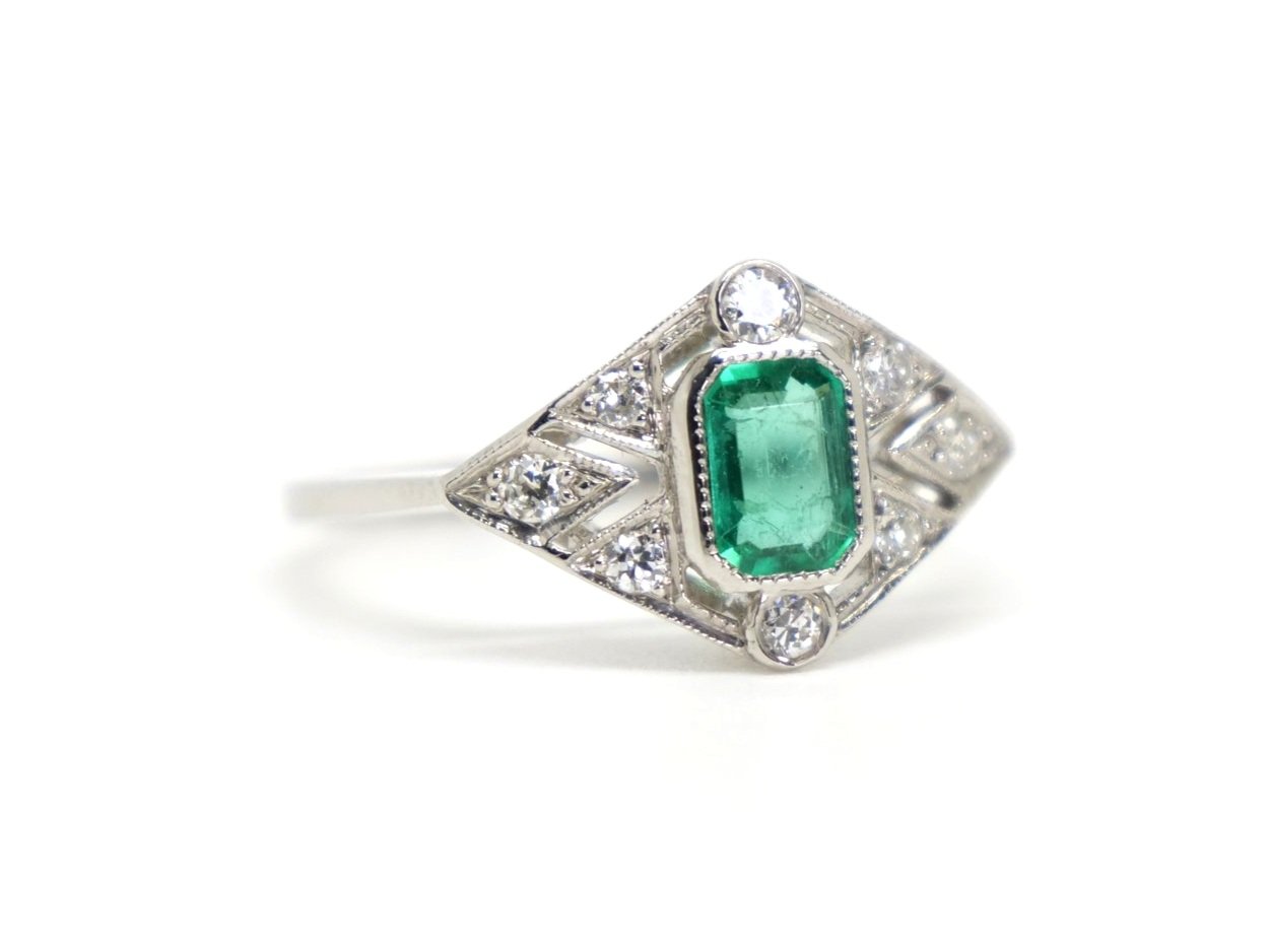 Very pretty Art Deco style platinum ring, set with an emerald cut emerald and set with diamonds in this lovely geometric design.