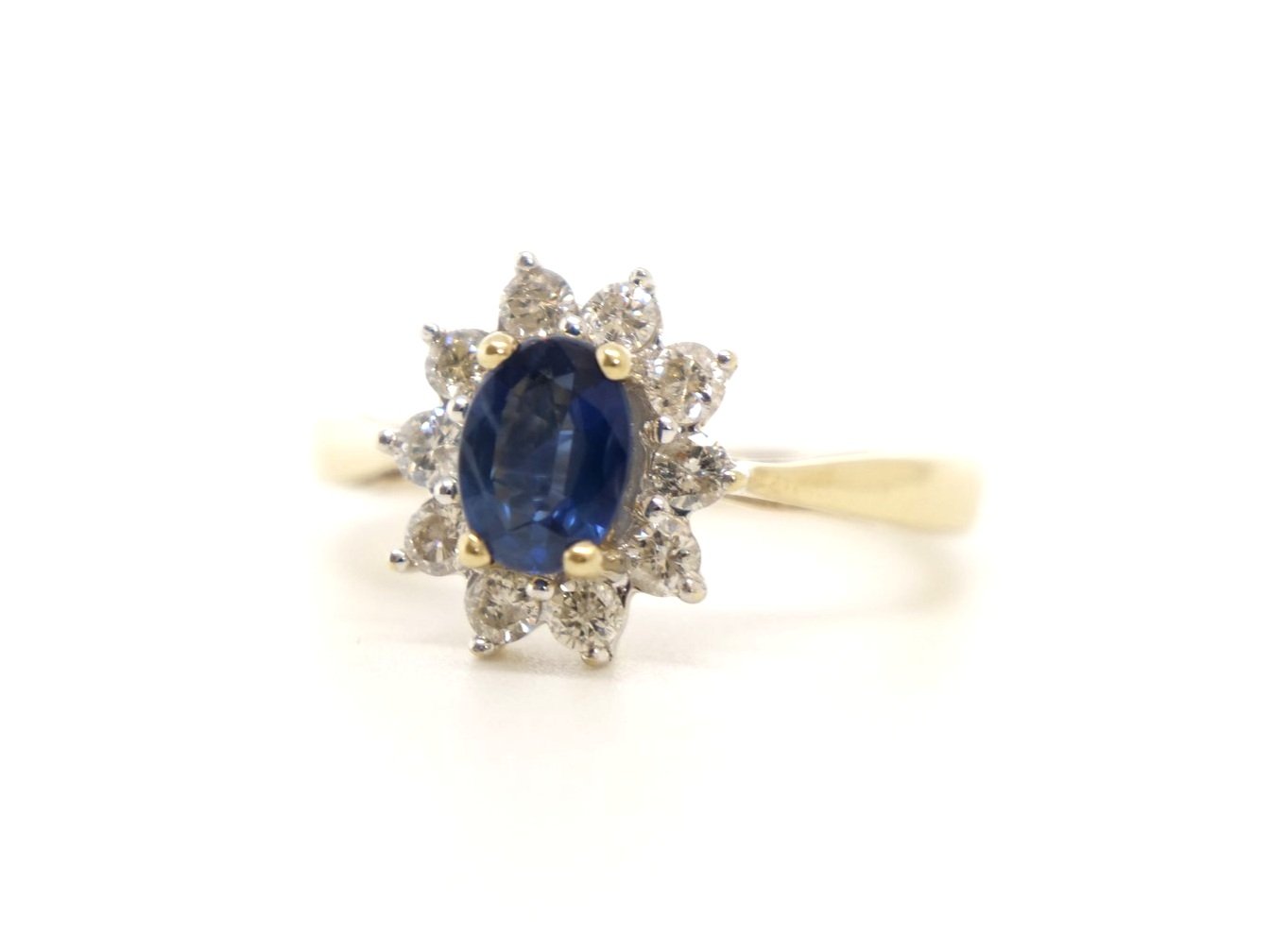 Lovely sapphire and diamond cluster ring, set with a 1ct oval cut mid blue sapphire and surrounded by 0.5ct brilliant cut diamonds.