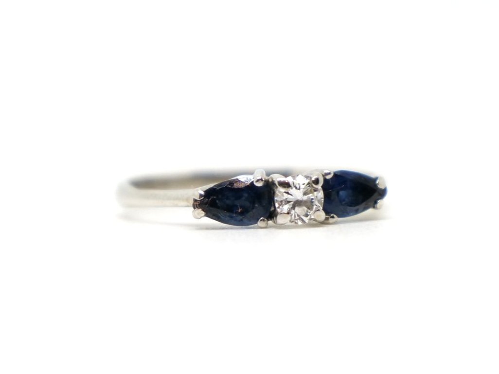Unusual and elegant 18ct gold sapphire and diamond ring, set with a central brilliant cut diamond, with a pear cut sapphire to each shoulder.
