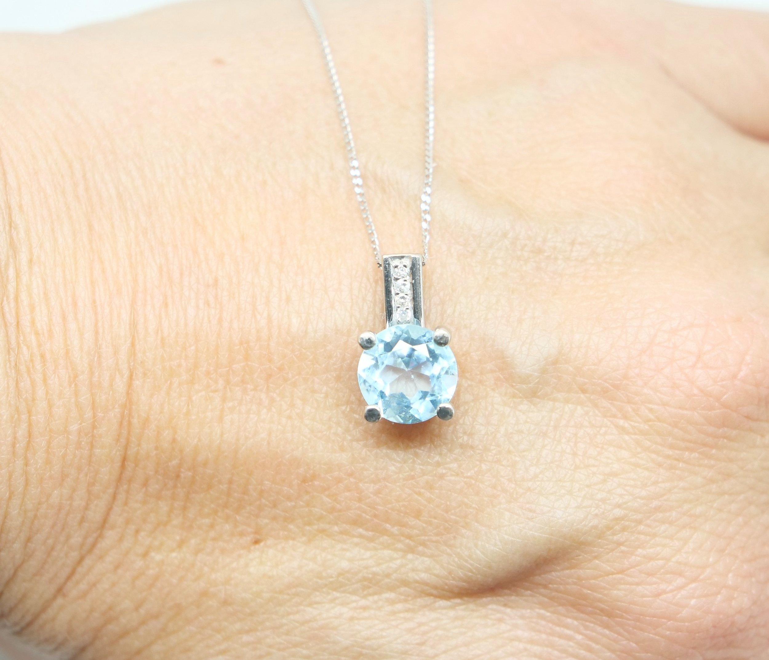 Very pretty 18ct gold blue topaz and diamond pendant and chain, with a round cut blue topaz with small diamonds above.