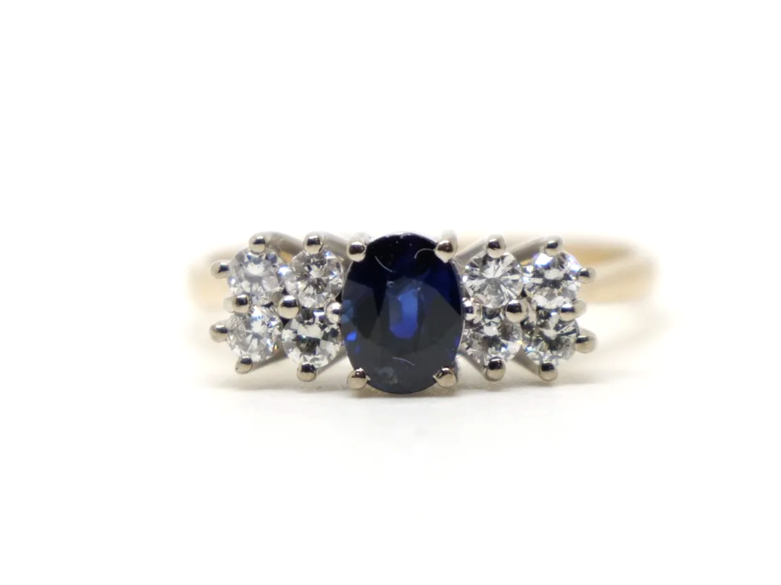 Unusual vintage 18ct gold sapphire and diamond ring, with a central oval cut 1ct sapphire and with four diamonds to each shoulder.