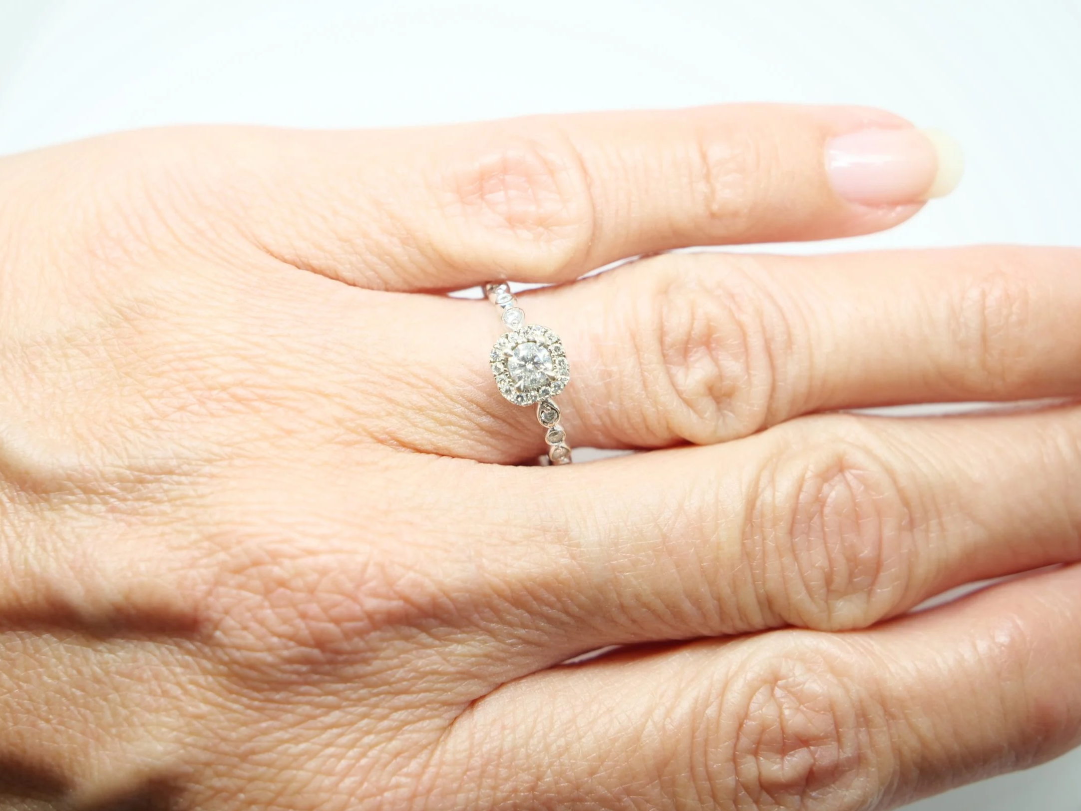 A platinum diamond halo ring by Emmy London, set with a round brilliant cut diamond at the centre surrounded by a cushion-shaped halo of smaller diamonds