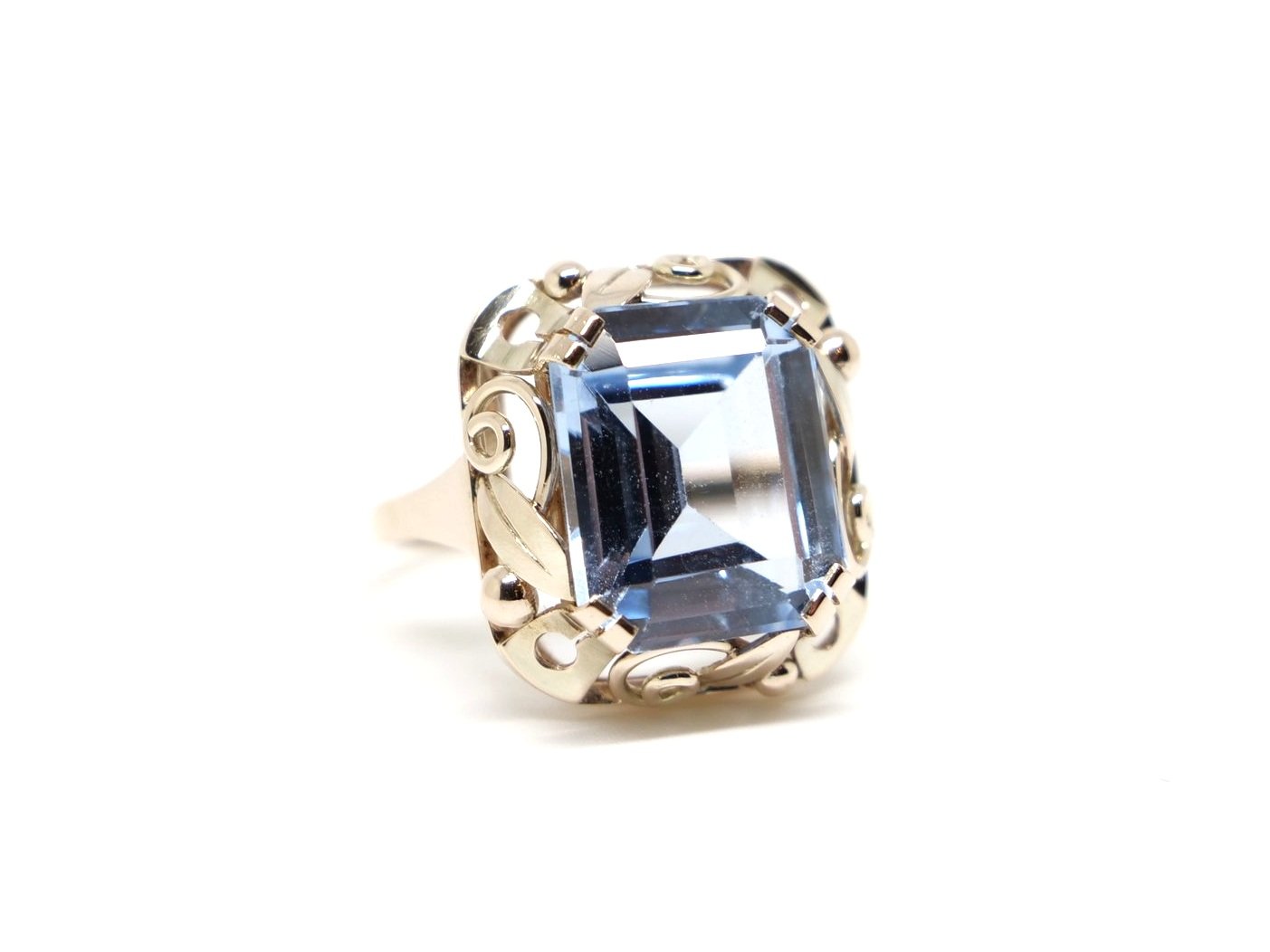 Beautiful vintage cocktail ring in 8ct gold, set with a large emerald cut blue spinel. Pretty gold scroll design all around the setting.