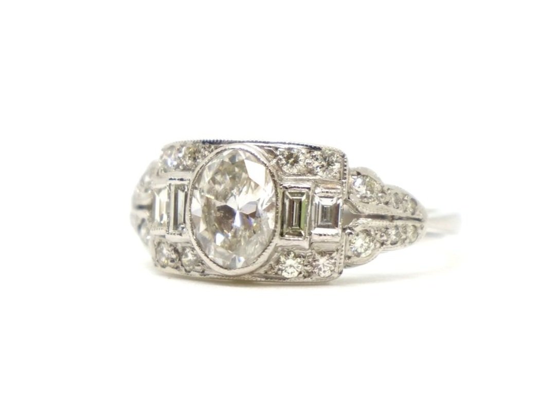 Superb diamond ring in platinum, set with a 1ct oval cut diamond and surrounded by further round and baguette cut diamonds. Approximate diamond total 1.5cts.