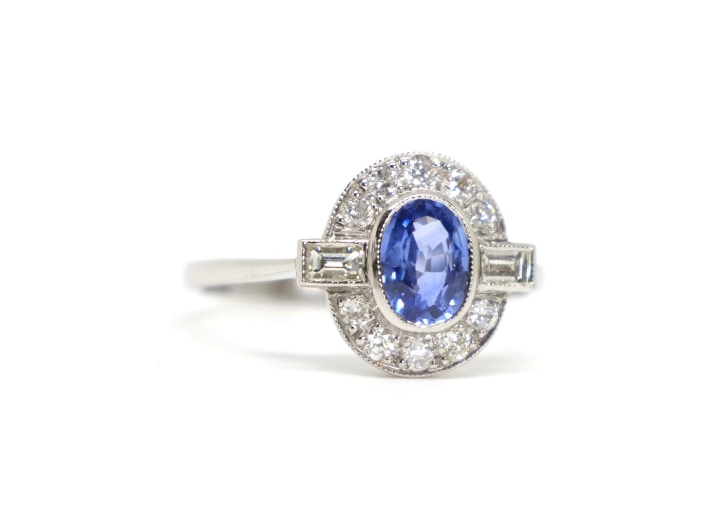 Very pretty Art Deco style platinum sapphire and diamond ring, set with an oval cut sapphire of approximately 1ct, with a baguette cut diamond to each shoulder.