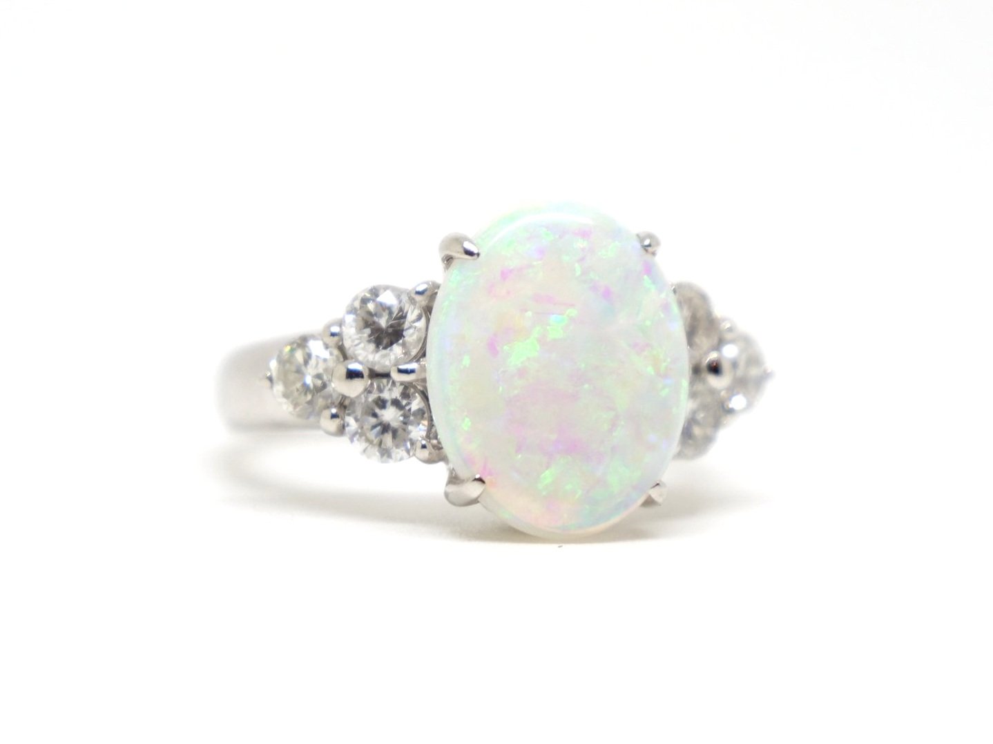 Stunning platinum opal and diamond ring, set with a beautiful opal with pink and green hues, with three diamonds to each side.
