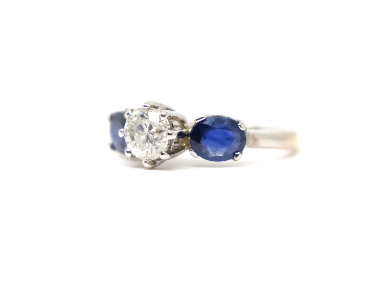 unusual vintage three stone ring in 18ct white gold with a round old cut diamond of approximately 1 carat at the centre, flanked by two oval cut sapphires of approximately 1.4 carats in total.