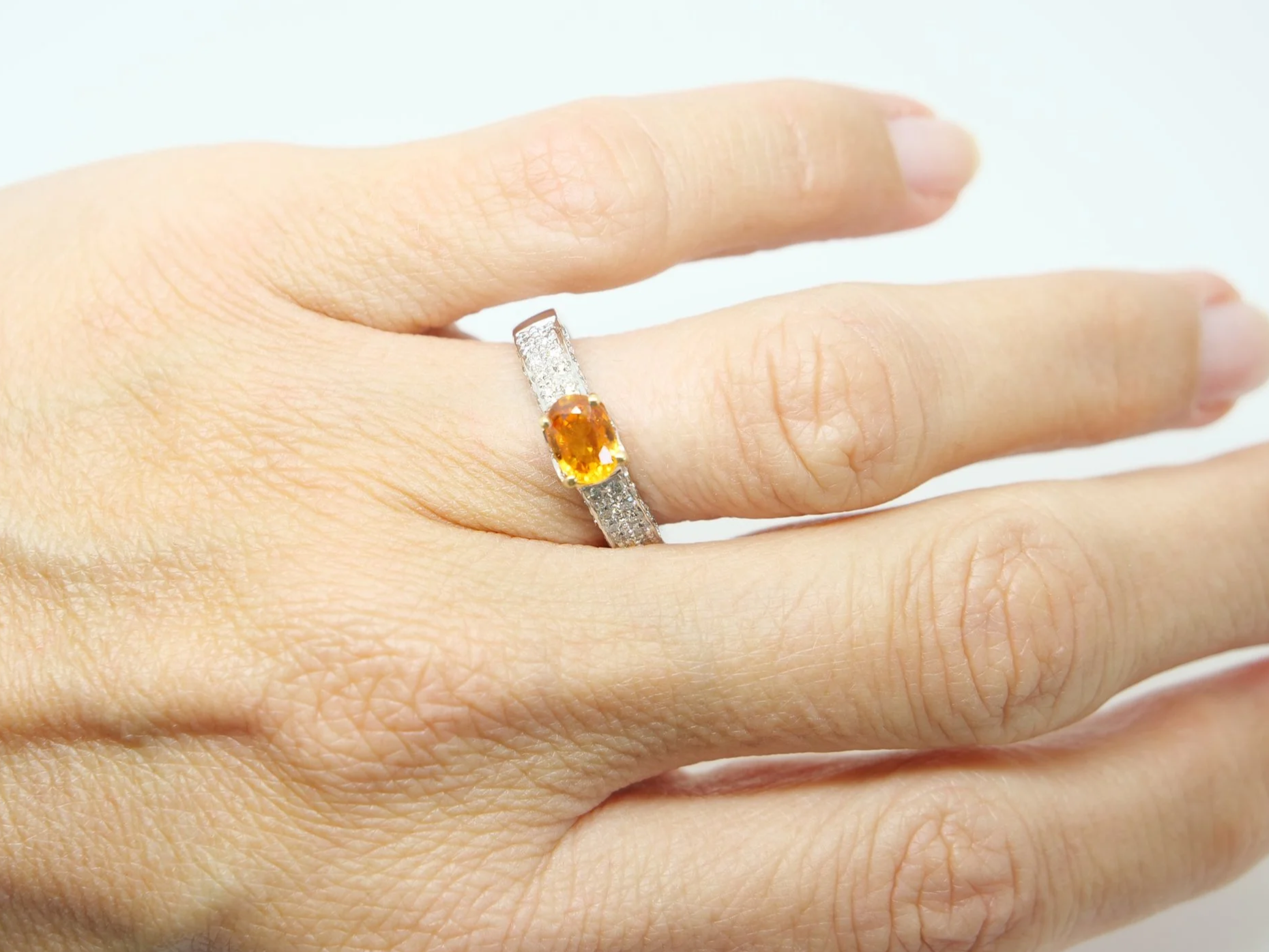 Beautiful 18ct gold orange sapphire and diamond ring, with a vibrant orange sapphire in an east-west setting, with pave style diamonds to each shoulder.