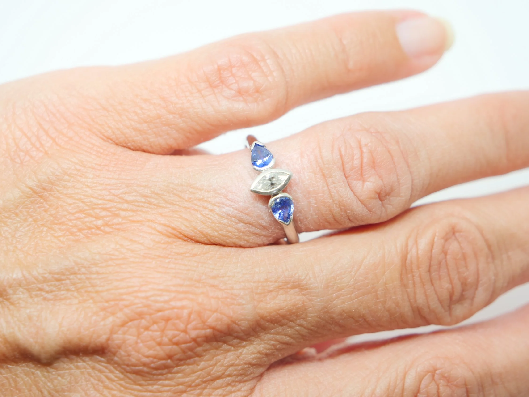 Beautiful platinum diamond and sapphire three stone ring, set with a marquise cut diamond and two pear cut sapphires.