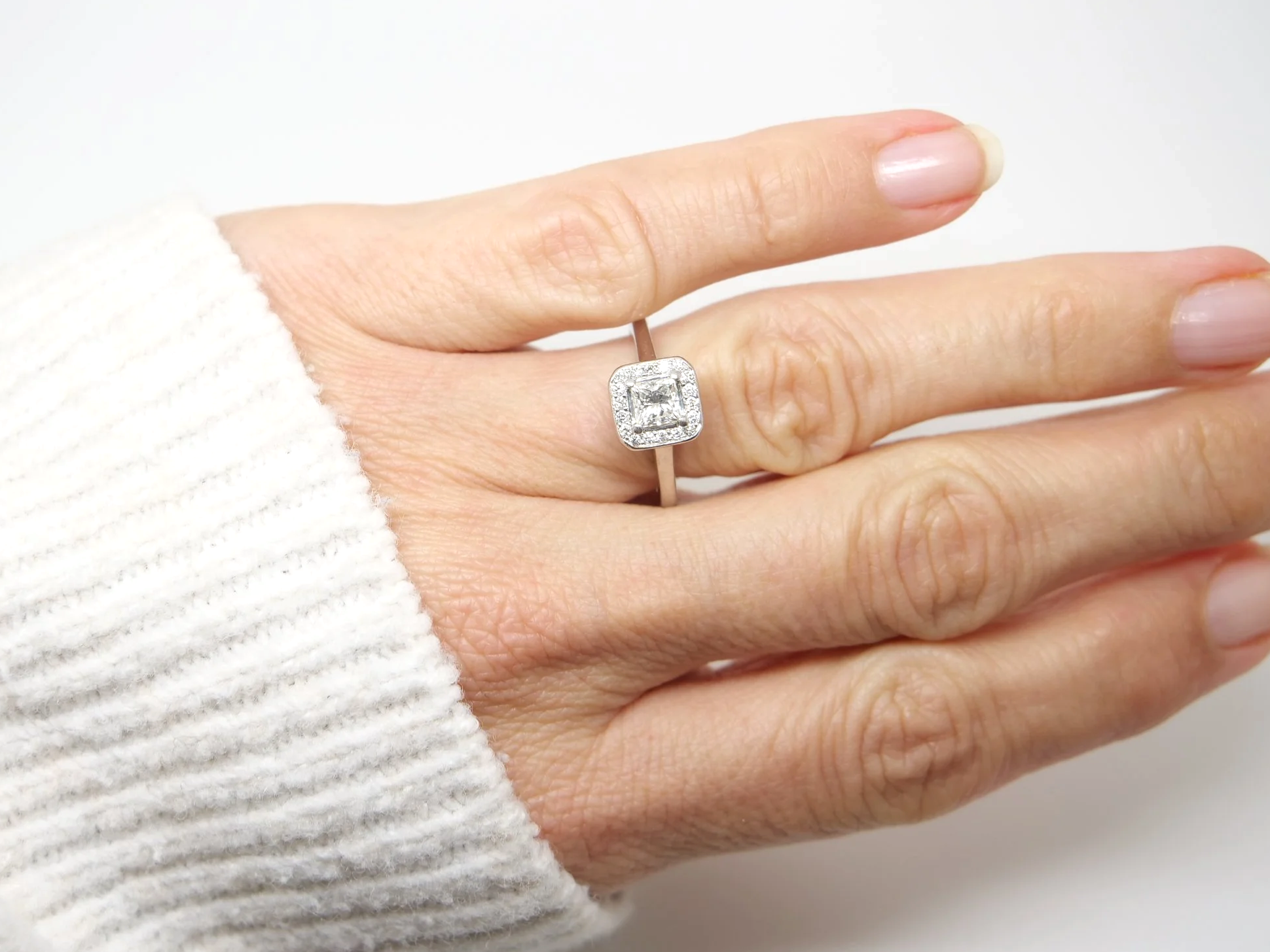 Beautiful platinum diamond ring, set with a central princess cut diamond of excellent quality and surrounded by a halo of diamonds.