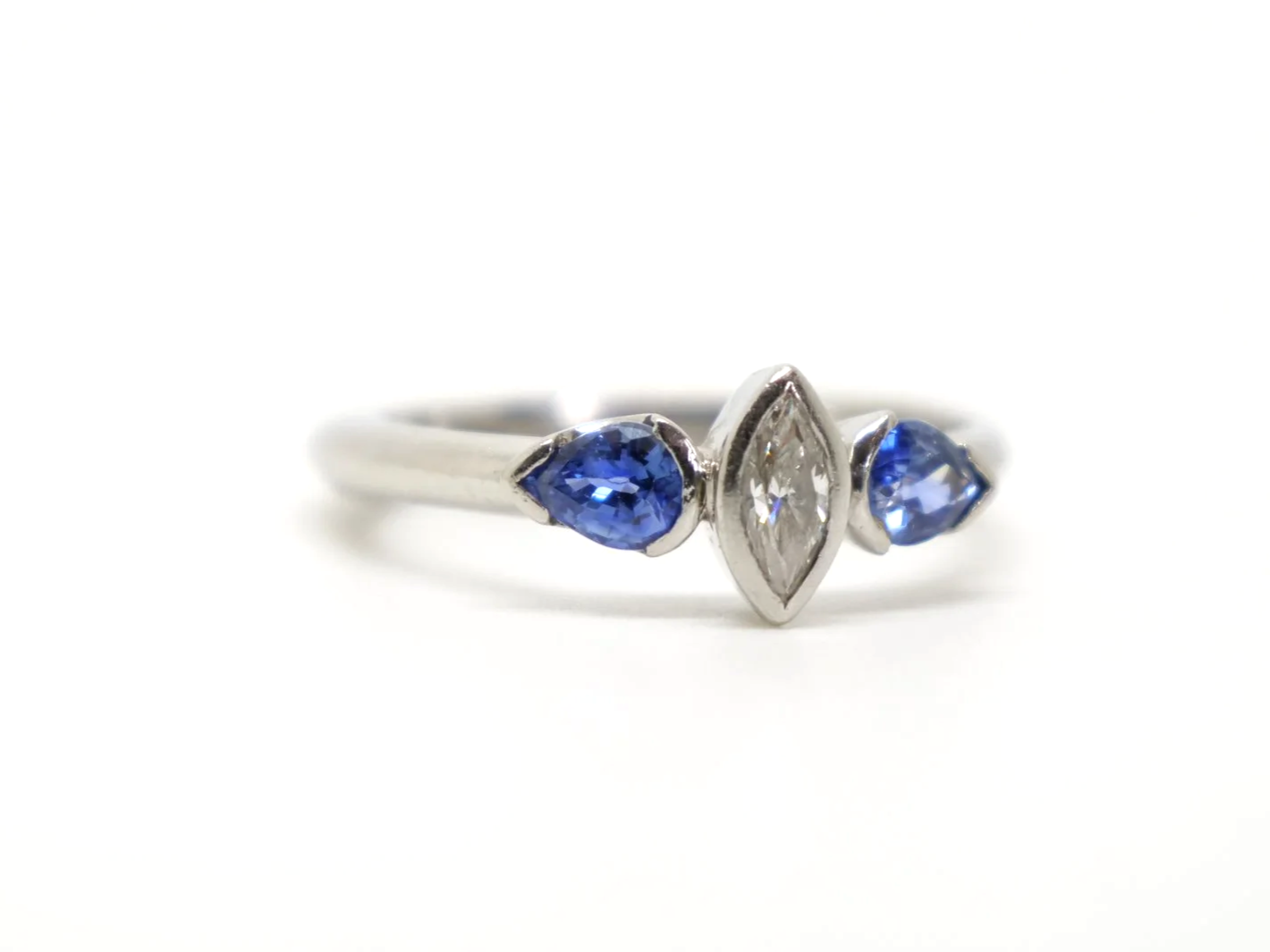 Beautiful platinum diamond and sapphire three stone ring, set with a marquise cut diamond and two pear cut sapphires.