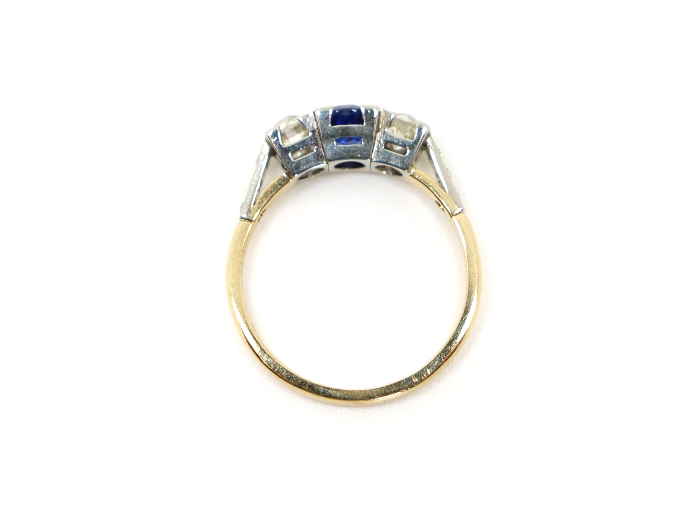 Stunning Art Deco 18ct gold sapphire and diamond trilogy ring, set with a central round cut sapphire and with a diamond to each side. Further diamonds to each shoulder.