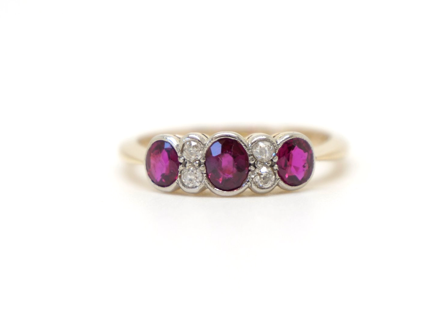 Vintage 18ct gold ruby and diamond ring, set with three oval cut rubies and inset with old cut diamonds.
