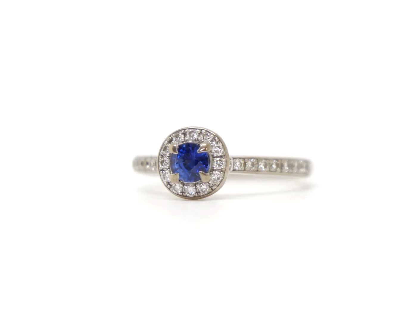 Lovely sapphire and diamond halo ring in 18ct white gold, set with a round-cut blue sapphire of approximately 0.35ct, and encircled by a halo of brilliant-cut diamonds
