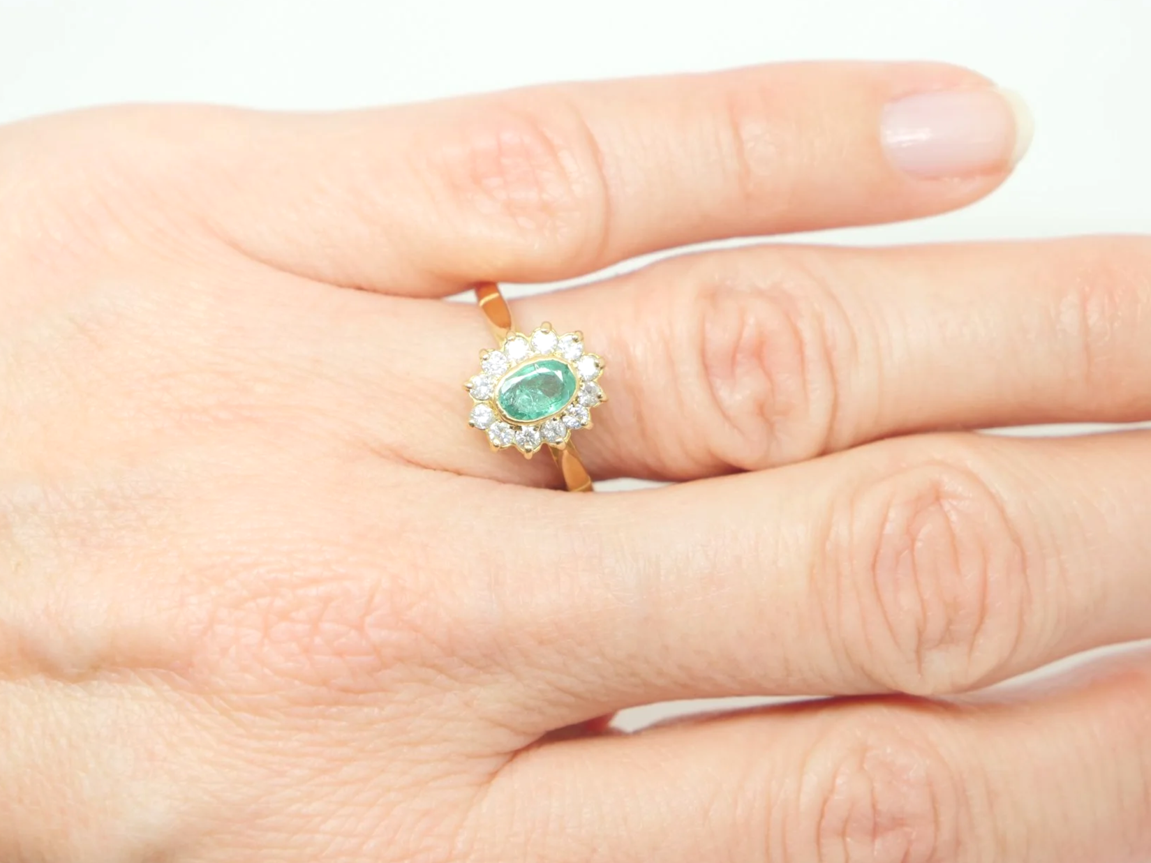 Classic vintage emerald and diamond cluster ring, set with a central oval cut emerald and surrounded by diamonds. All set in 18ct gold.