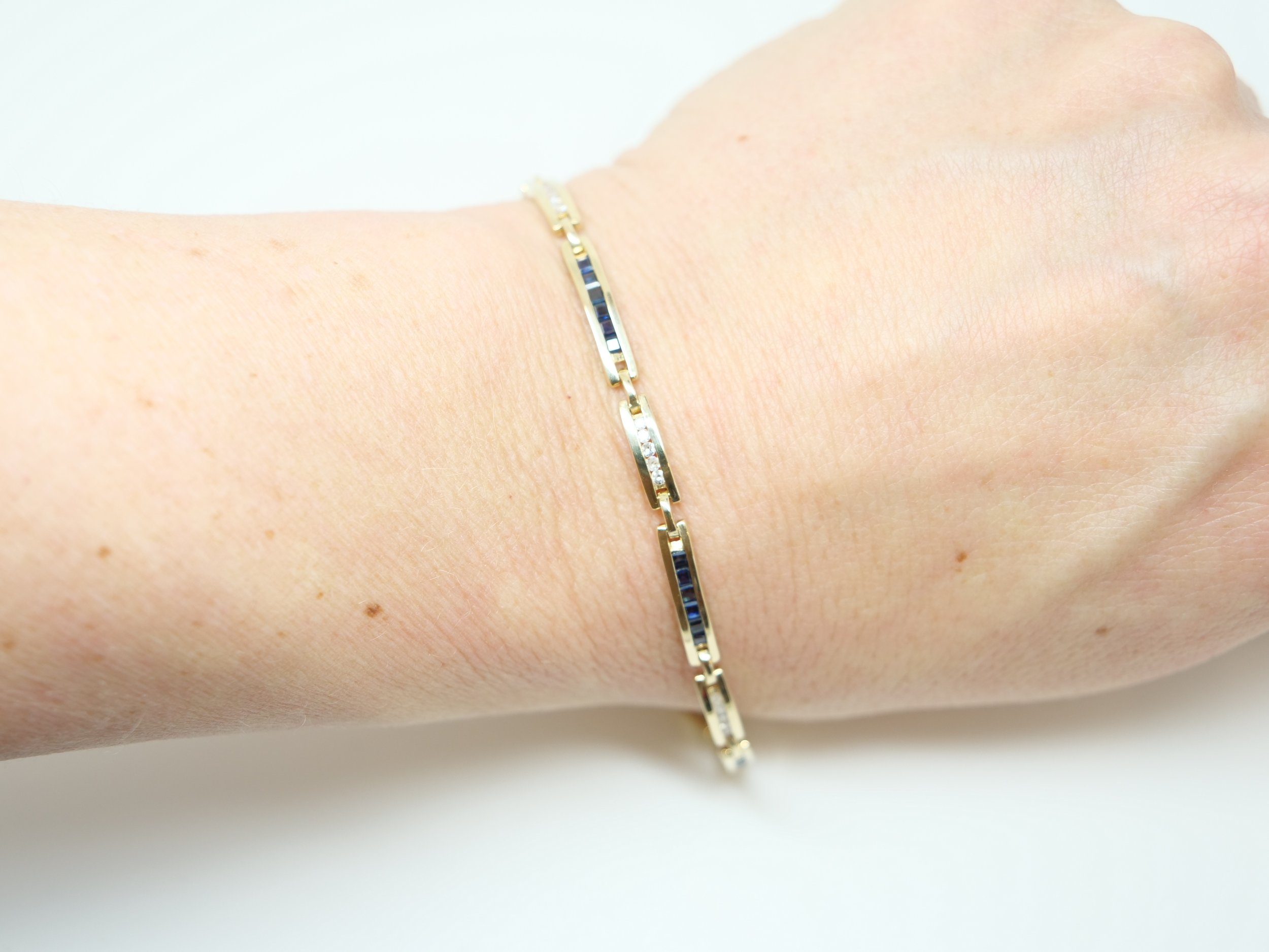 An elegant 9ct yellow gold bracelet set with alternating channel-set sapphires and diamonds in a clean, repeating design.