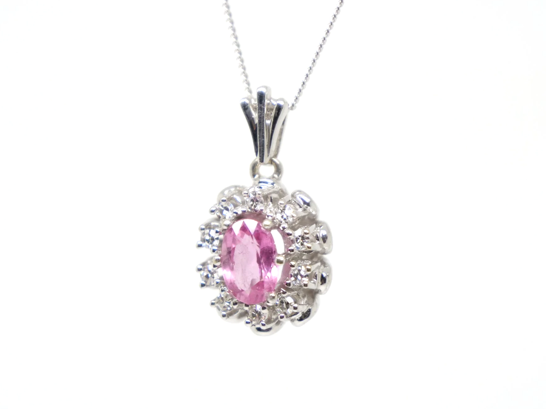 vintage 14ct white gold pink sapphire and diamond cluster pendant, set with a striking oval cut pink sapphire and surrounded by diamonds.