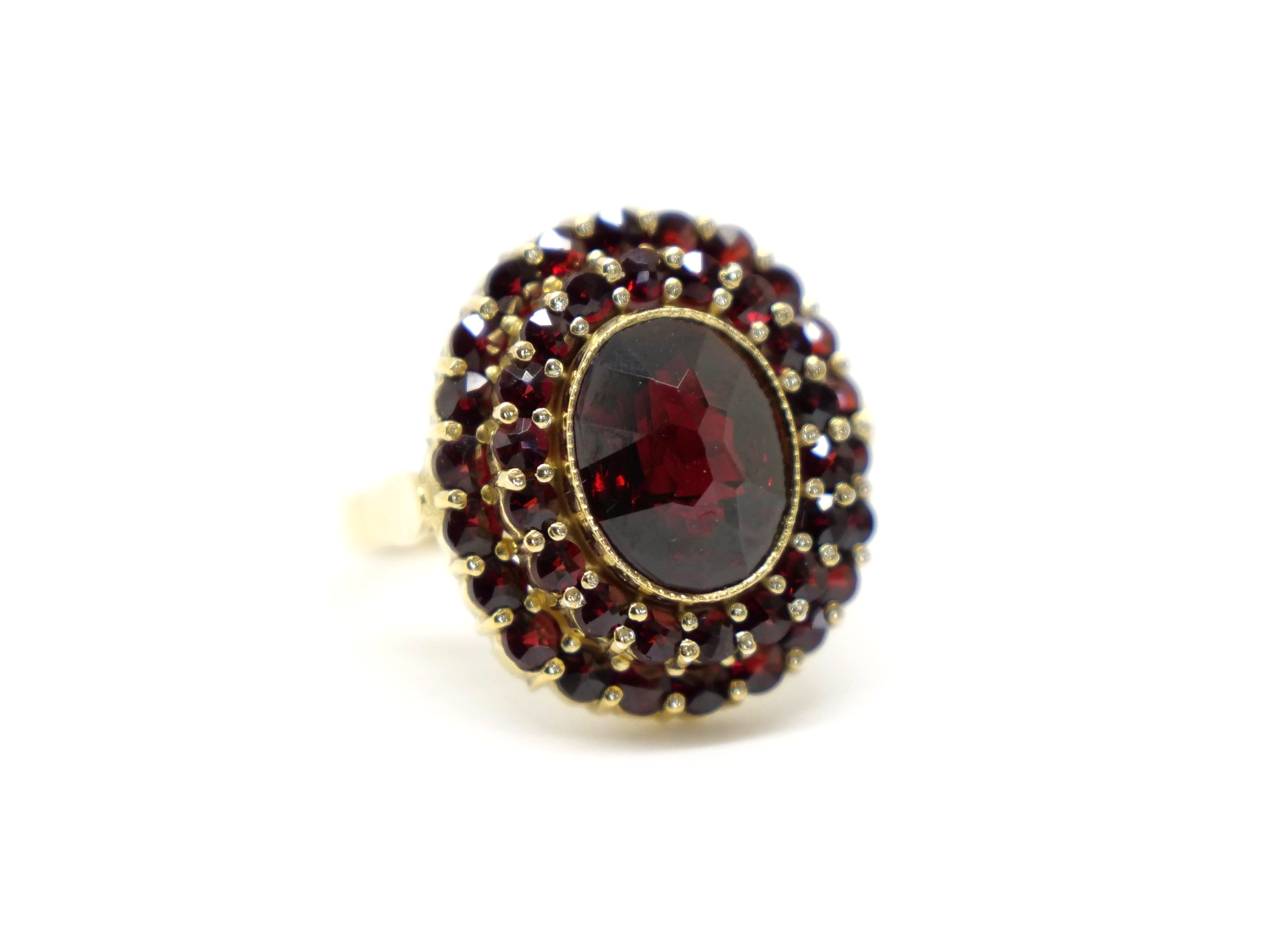 Beautiful 18ct gold garnet cocktail ring, set with an oval cut central garnet and surrounded by two rows of further garnets.