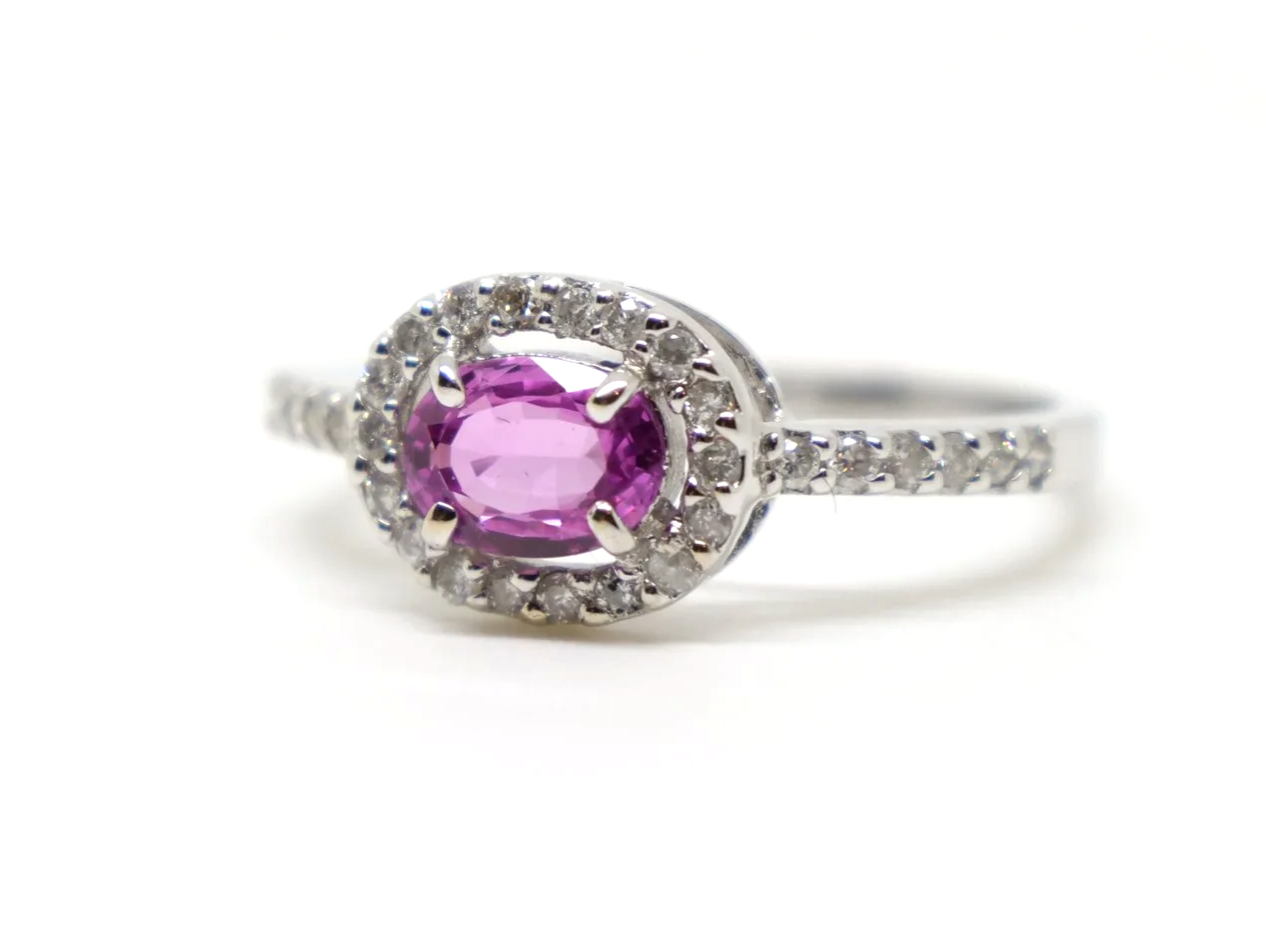 Very sparkly contemporary 18ct gold pink sapphire and diamond ring, set with an oval cut east-west pink sapphire, with a diamond halo. Further diamonds to the shoulders.