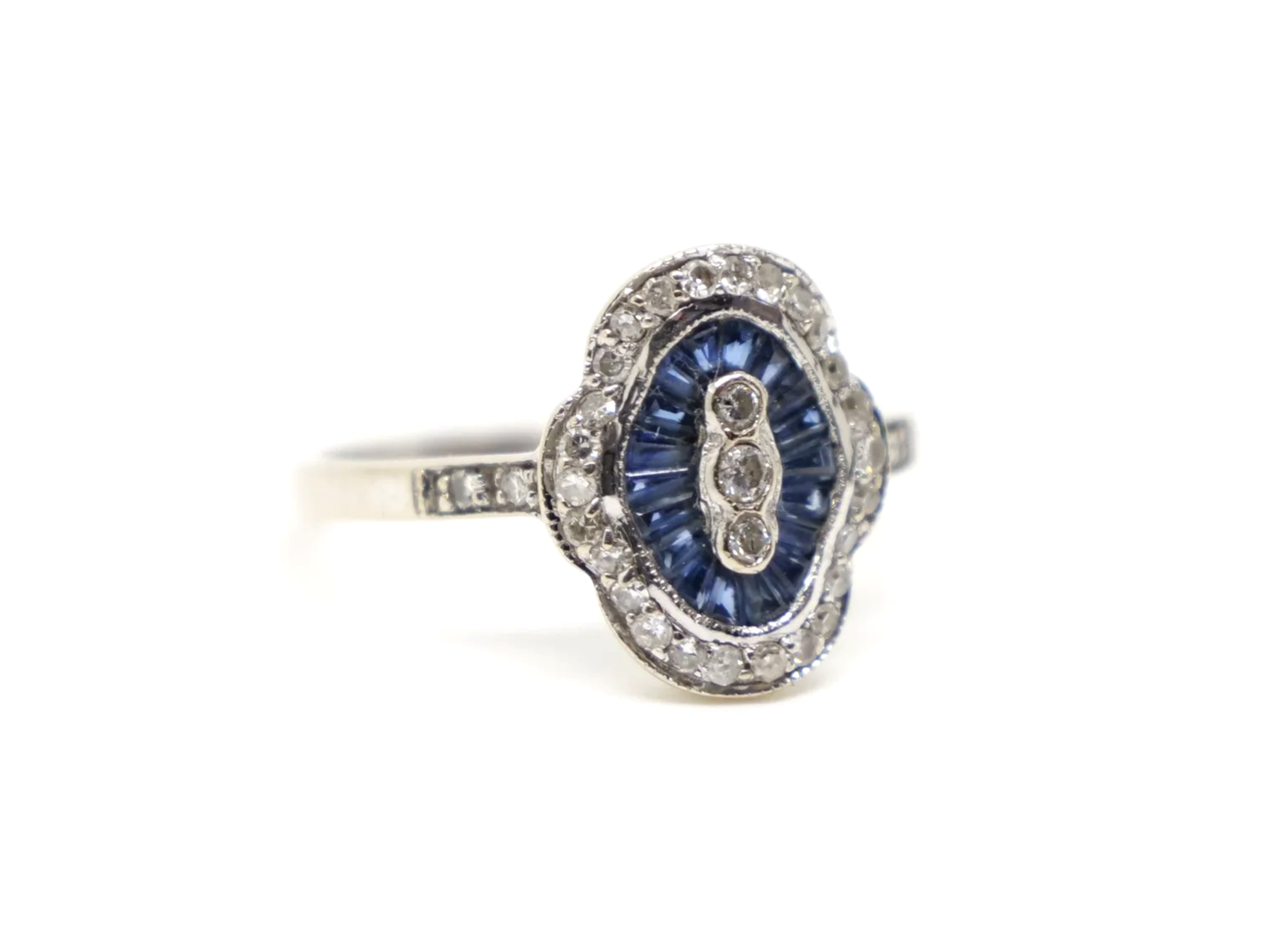 Unusual 18ct gold sapphire and diamond ring in this lovely Art Deco design. Set with calibre cut sapphires and small diamonds.