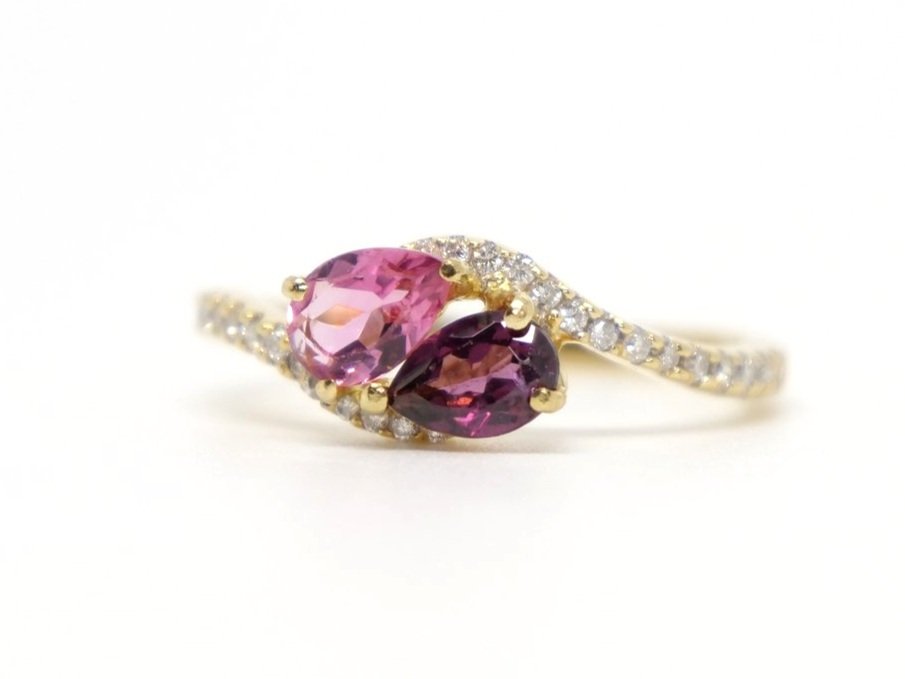 Very unusual 18ct gold ring, set with a pear cut pink tourmaline and a pear cut almandine garnet in this lovely twist design. Very pretty diamonds set into each shoulder.