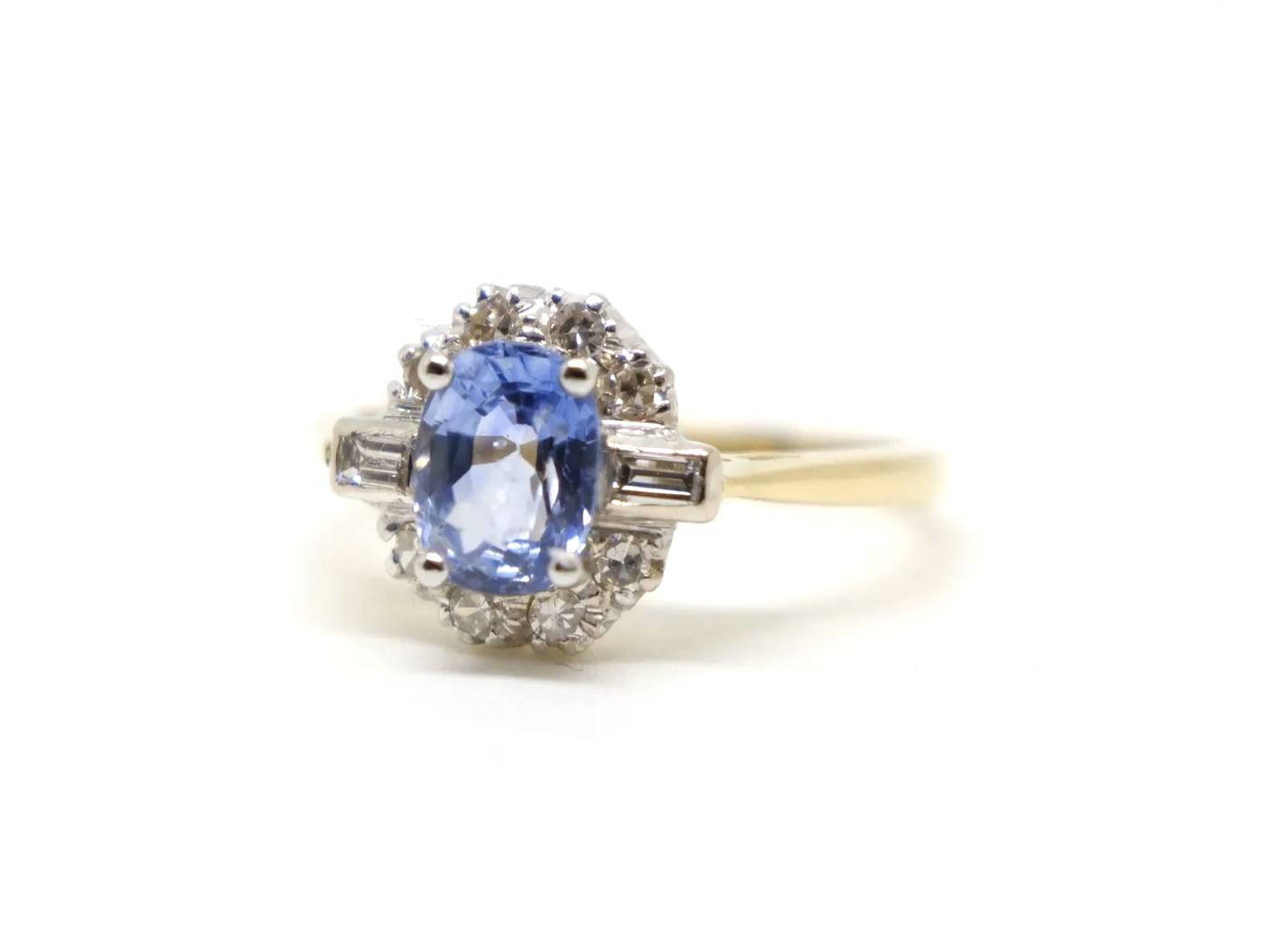 Stunning 18ct gold sapphire and diamond ring, set with an oval light blue sapphire and surrounded by diamonds, with a baguette diamond to each shoulder.