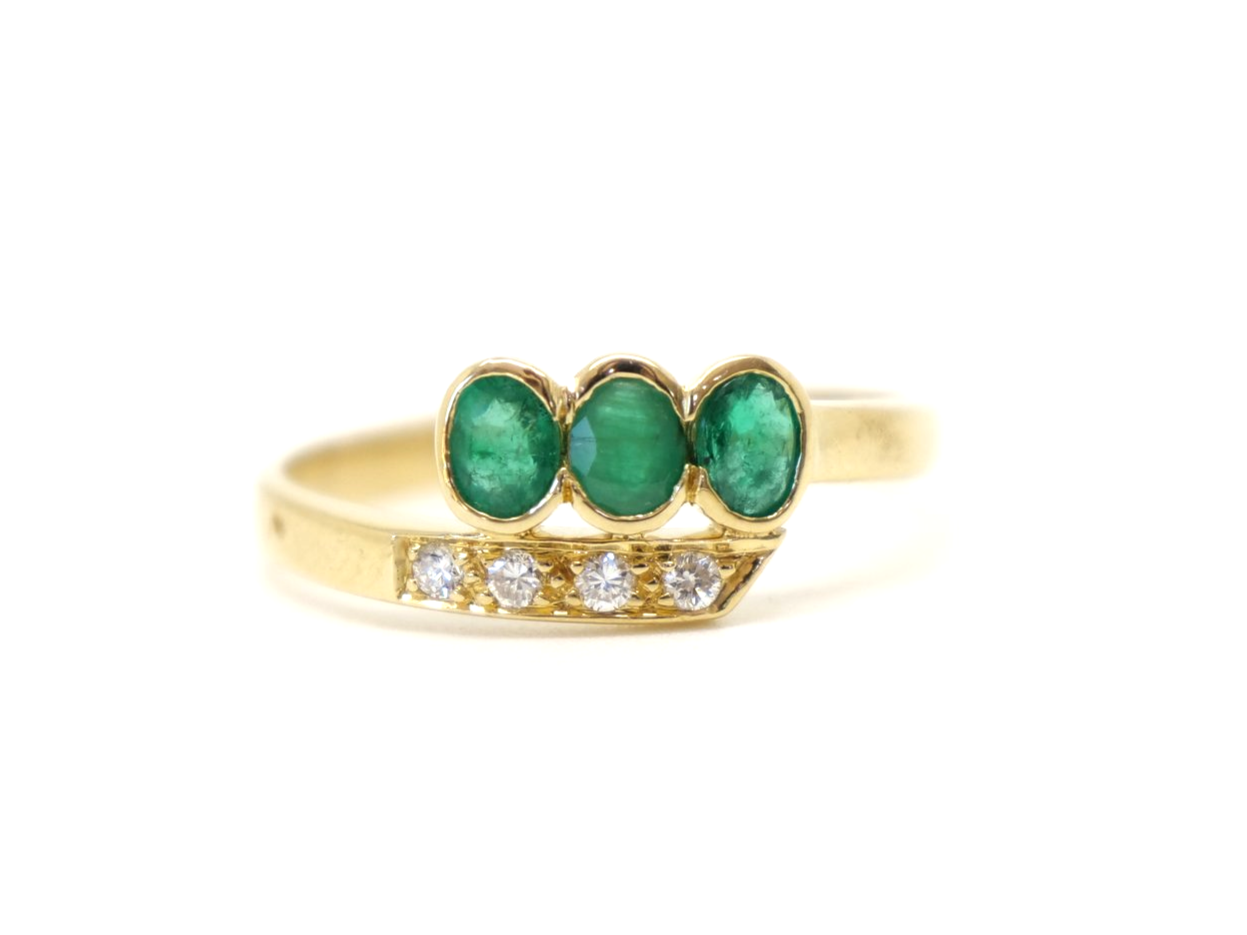 Unusual 18ct gold emerald and diamond twist design ring, set with three oval cut emeralds and four small diamonds.