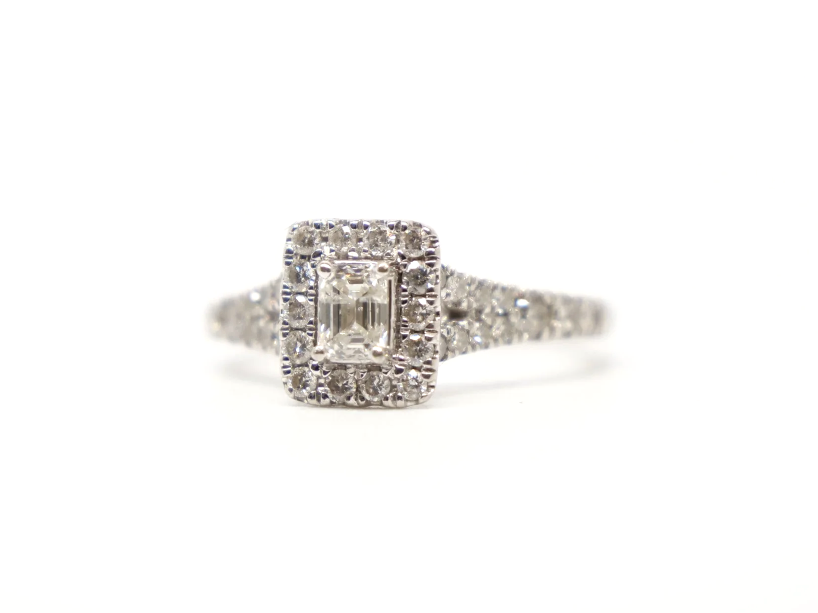 platinum diamond cluster ring set with an emerald-cut diamond at the centre, surrounded by a rectangular pavé-set halo of round brilliant-cut diamonds
