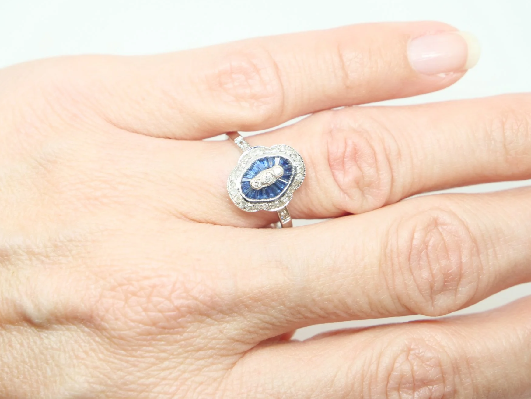 Unusual 18ct gold sapphire and diamond ring in this lovely Art Deco design. Set with calibre cut sapphires and small diamonds.