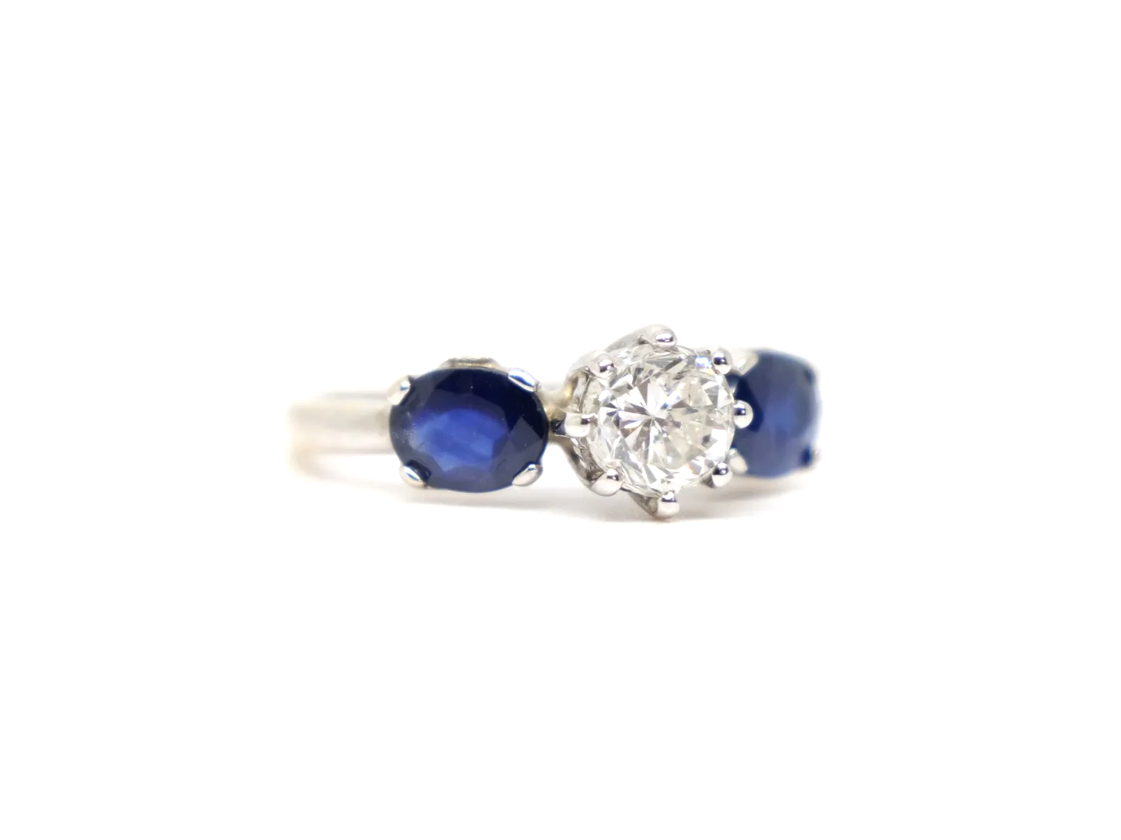 unusual vintage three stone ring in 18ct white gold with a round old cut diamond of approximately 1 carat at the centre, flanked by two oval cut sapphires of approximately 1.4 carats in total.