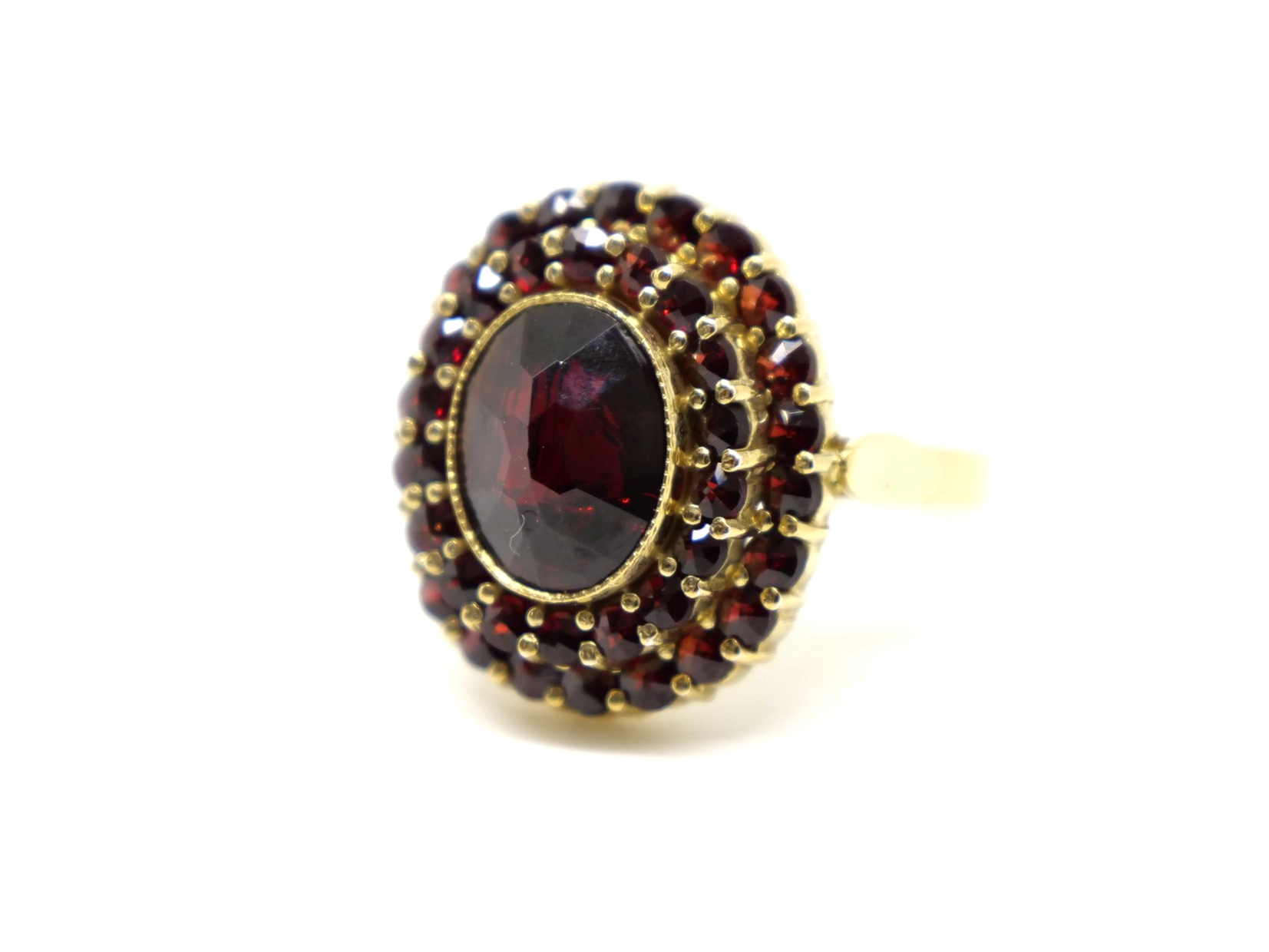 Beautiful 18ct gold garnet cocktail ring, set with an oval cut central garnet and surrounded by two rows of further garnets.