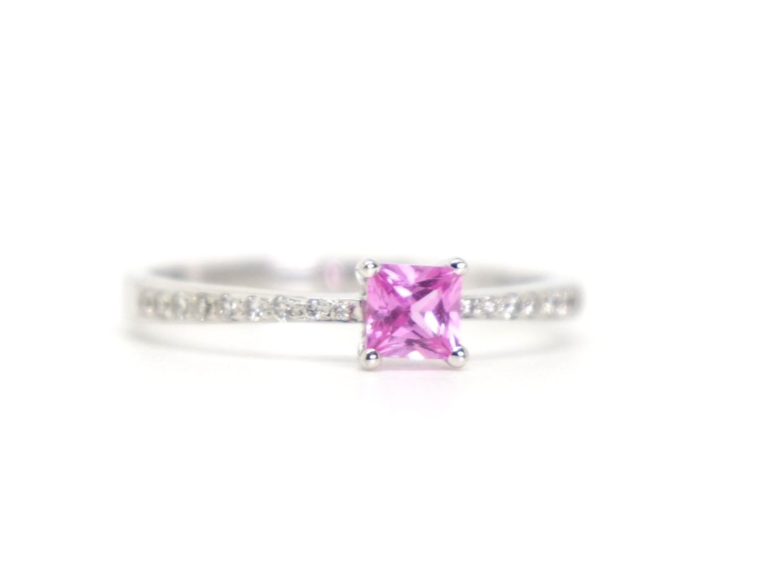 18ct gold pink sapphire and diamond ring, with a central princess cut pink sapphire, and diamonds in shoulders.